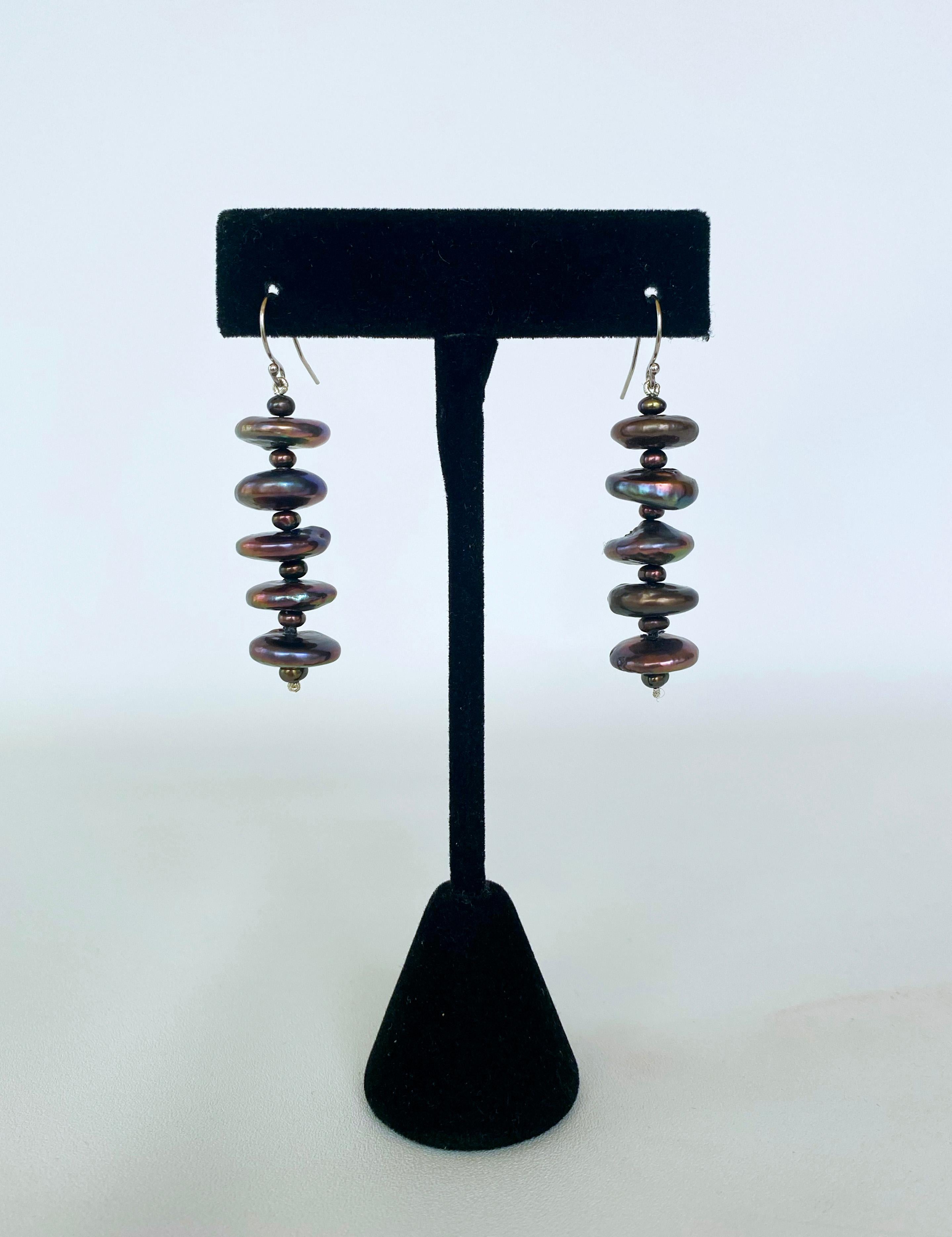 Beautiful yet simple flat Black Pearl earrings with small Black Pearl beads in between. This pair features Peacock / Oil spill Pearls that display a beautiful luster and sheen. Measuring a total of 2.25 inches long and hanging from a 14K White Gold