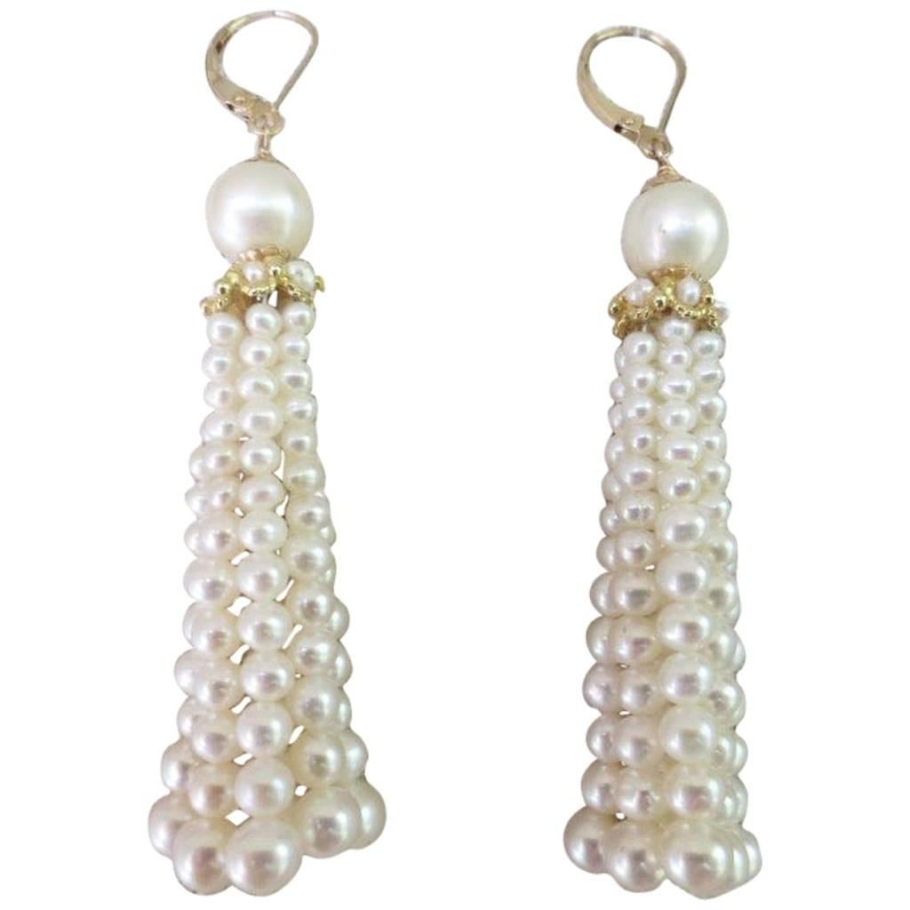 Elegant tassel earrings by Marina J, in strands of cultured pearls, graduated in size from 4 1/2 to 3 mm and topped by a cultured pearl measuring 6 mm, below which is a gold roundel through which the tassels emanate. The wire is yellow gold. The