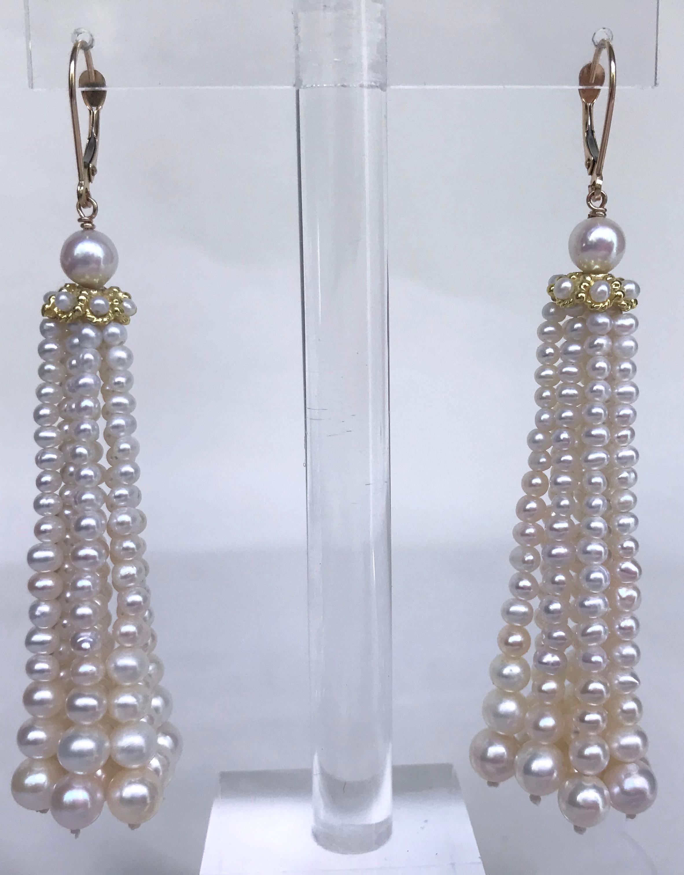 Elegant tassel earrings by Marina J, in strands of cultured pearls, graduated in size from 4 1/2 to 3 mm, and topped by a cultured pearl measuring 6 mm, below which is a gold rondell through which the tassels emanate. The wire is yellow gold. The