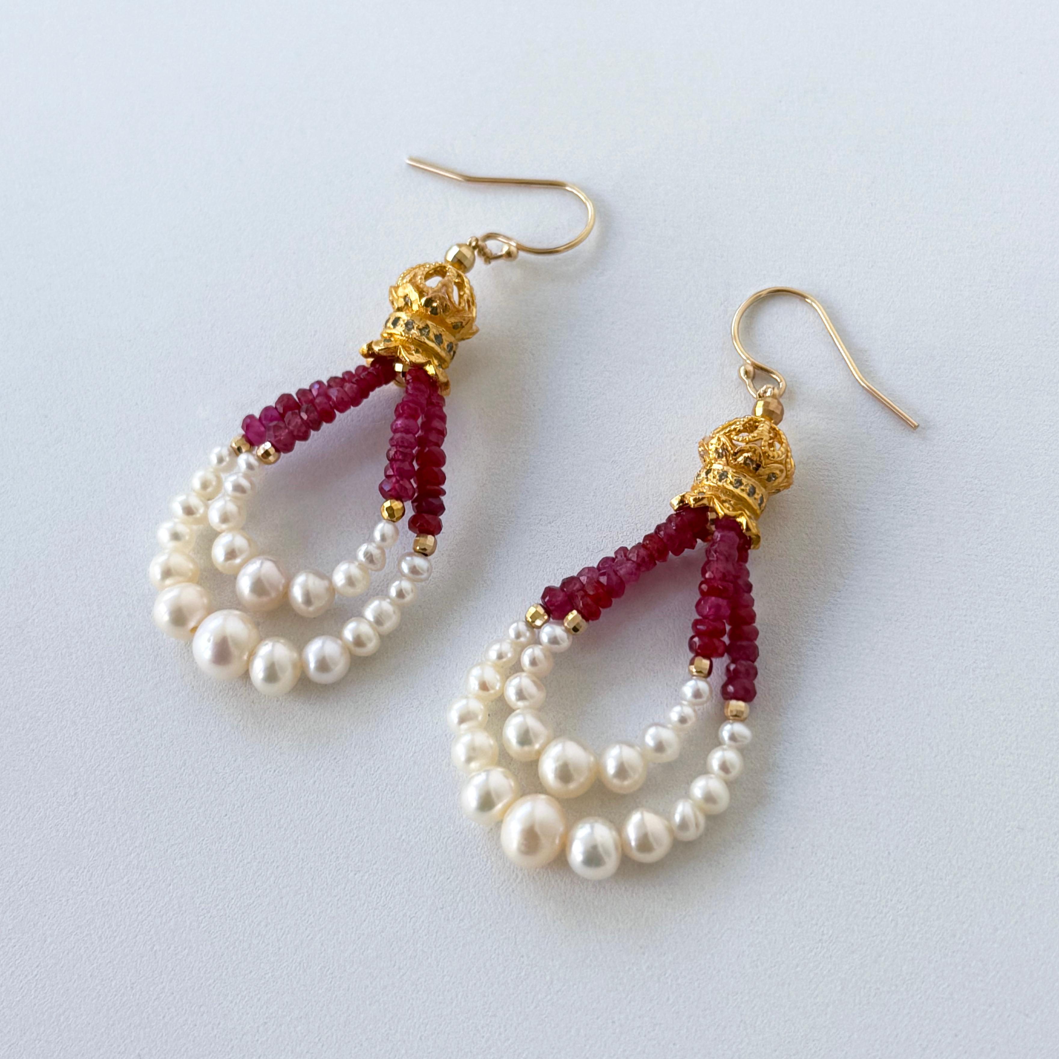 Magnifiques boucles d'oreilles pendantes d'inspiration princesse par Marina J.
Cette paire présente de magnifiques cloches décoratives plaquées or jaune 18 carats, auxquelles sont suspendus deux fils arrondis de rubis rouges facettés, de boucles en