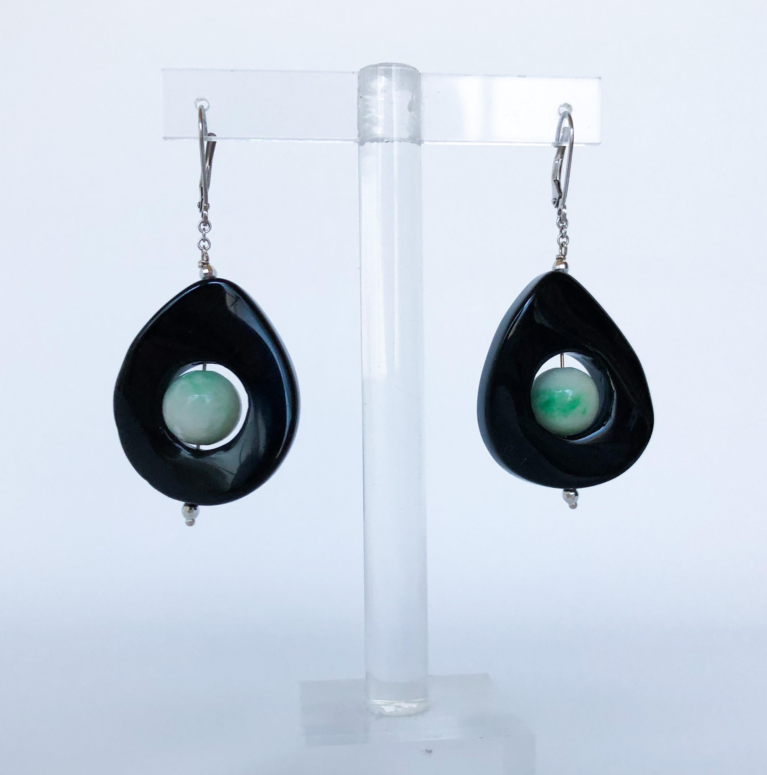These earrings are made with jade circular beads and are enclosed in black onyx rings. There is a hint of shine from two tiny white gold beads. They measure about 2 inches long, which will hang beautifully and compliment any look. The wiring and