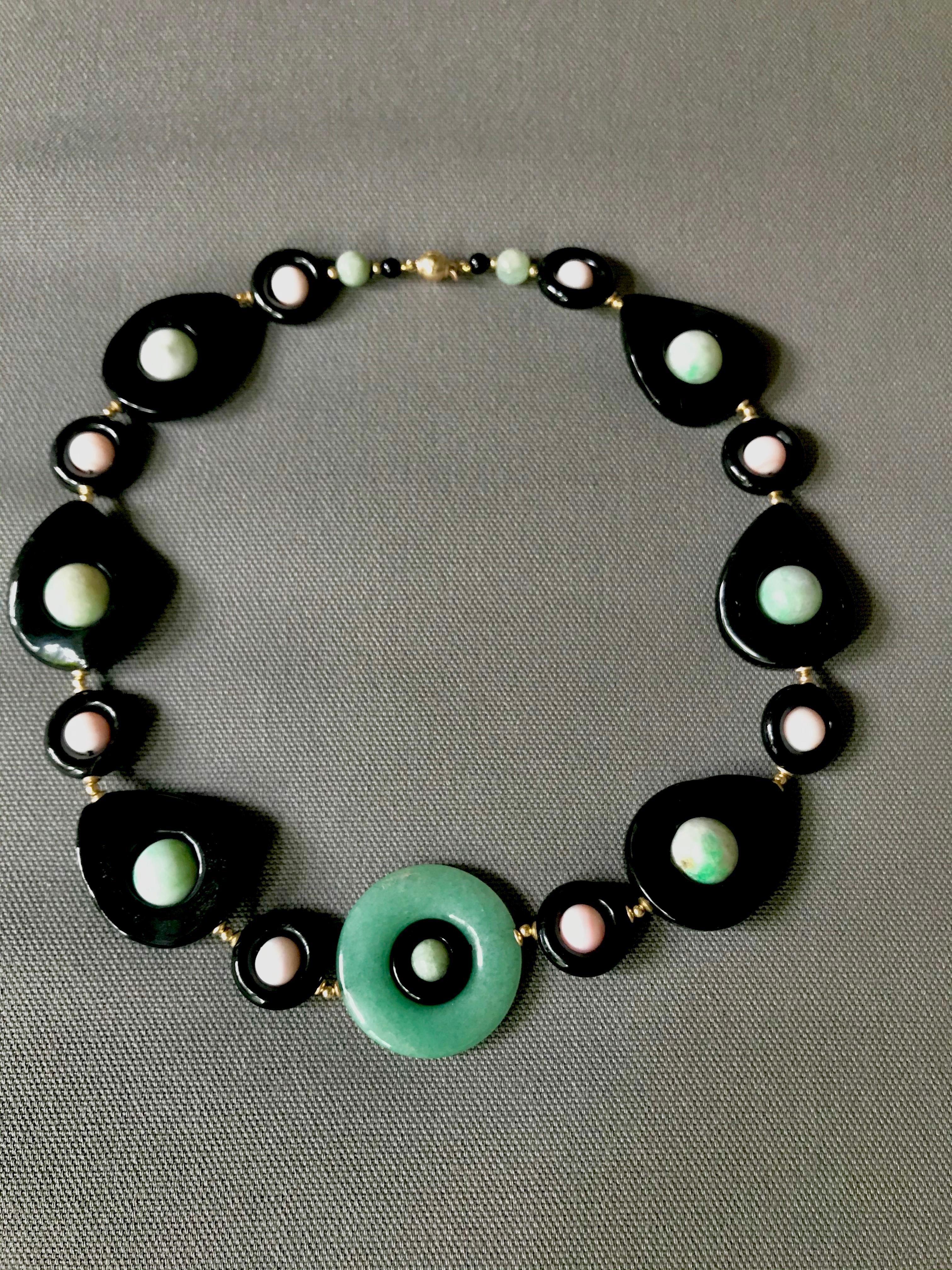 Marina J.'s unique art deco style necklace features a variety of shapes :onyx  spheres, pink coral round beads with inner round and outer circular Jade. . This striking piece mimics jewelry from the roaring '20s with its symmetrical design and