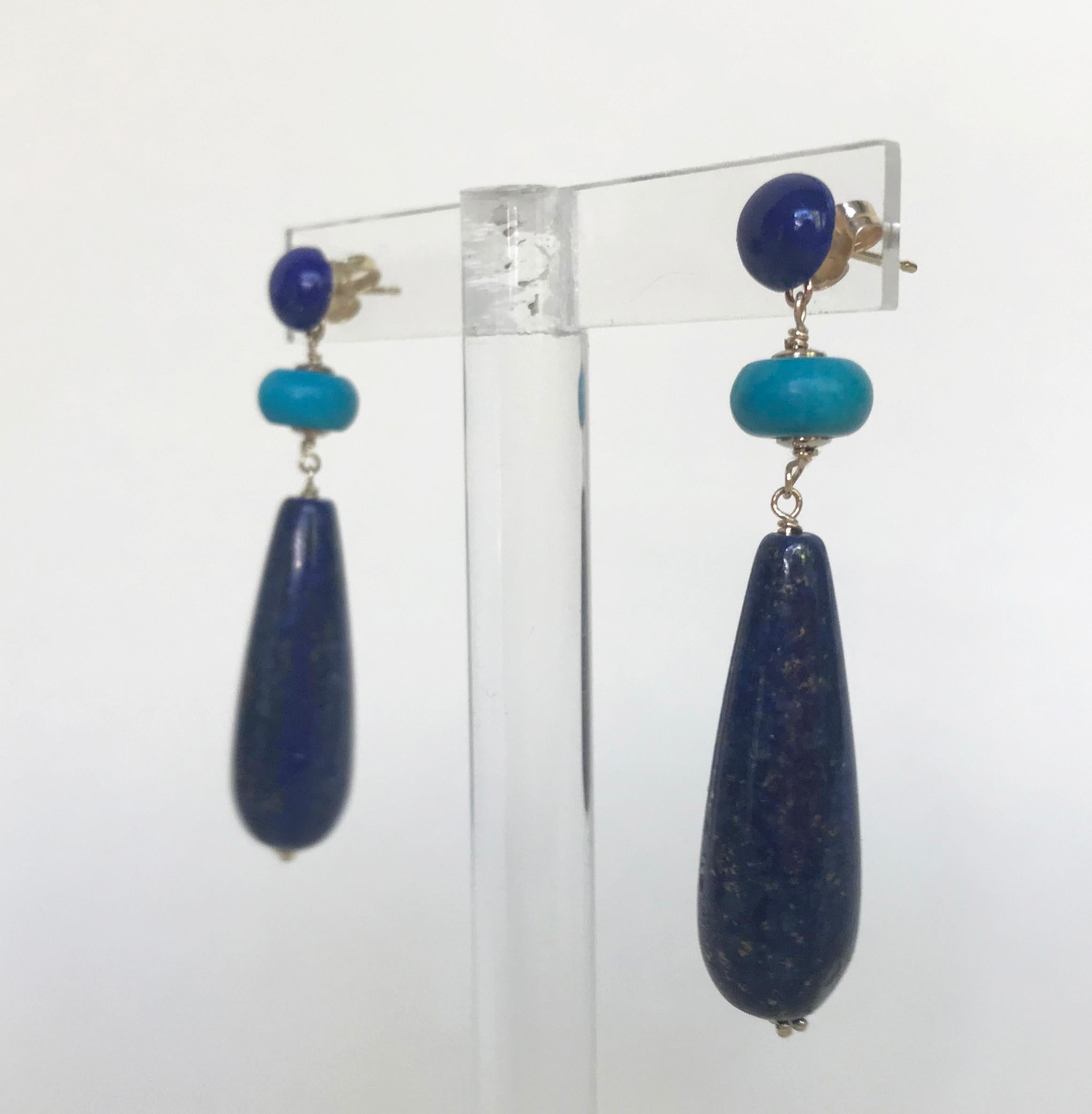 This lapis lazuli and turquoise earrings are highlighted with 14k yellow gold wiring and stud.  Accenting the deep blue of the lapis lazuli studs are light blue turquoise beads hanging above. Completing the look there is a lapis lazuli drop bead. At