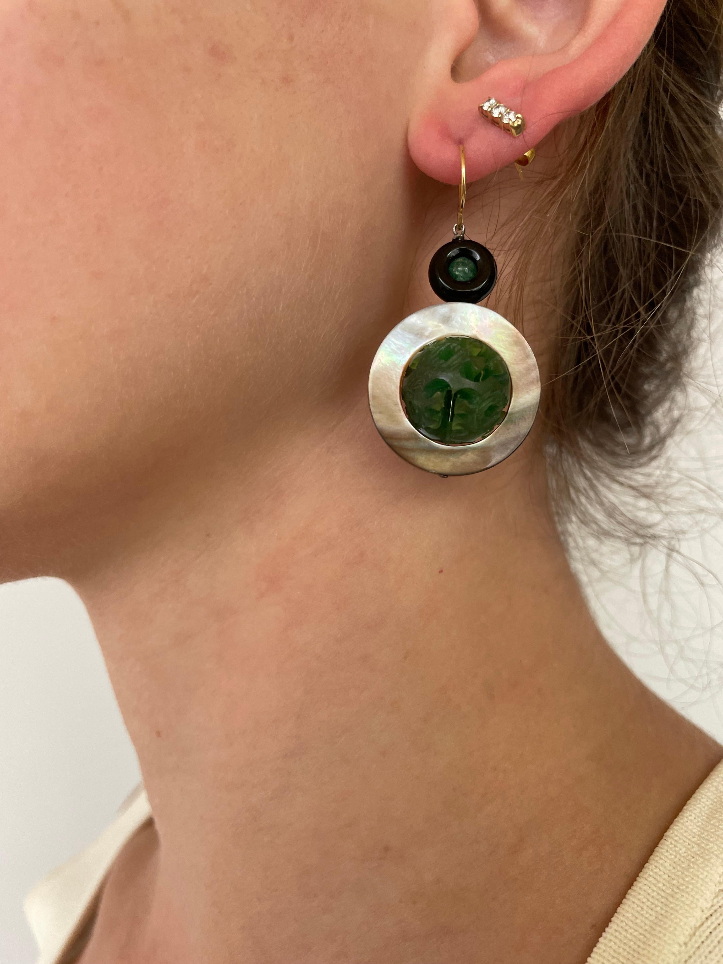 Striking pair of earrings made by Marina J. Measuring 2 inches long, these earrings feature vintage Bakolite from the 1930's reworked into this pair. A small but vibrant Emerald Bead sits inside a Black Onyx Ring, from which a Mother of Pearl Ring