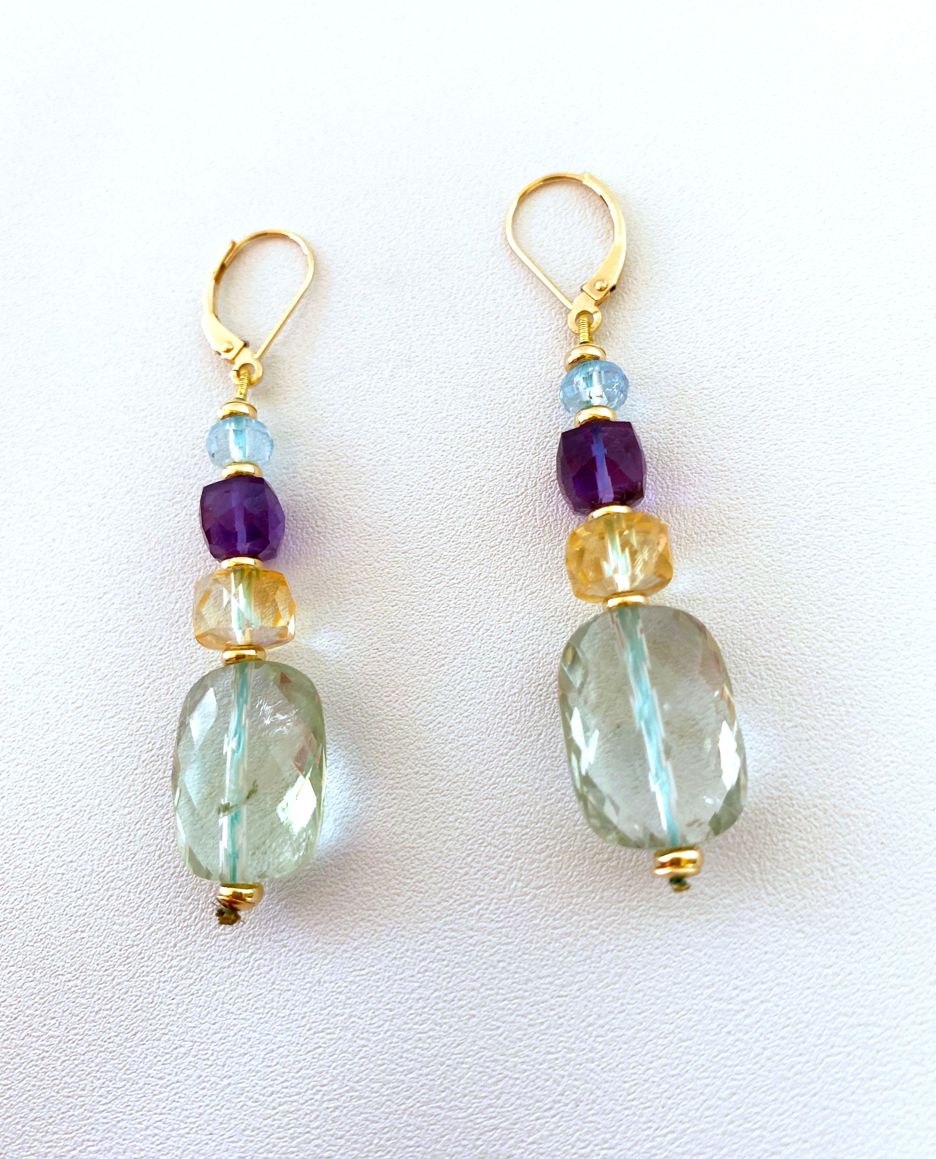 Jolie paire de la collection « Alexis ». Les boucles d'oreilles pendantes graduées et colorées sont réalisées avec des perles d'aigue-marine brillante, d'améthyste violette, de citrine et d'améthyste verte de différentes formes. Suspendue à des