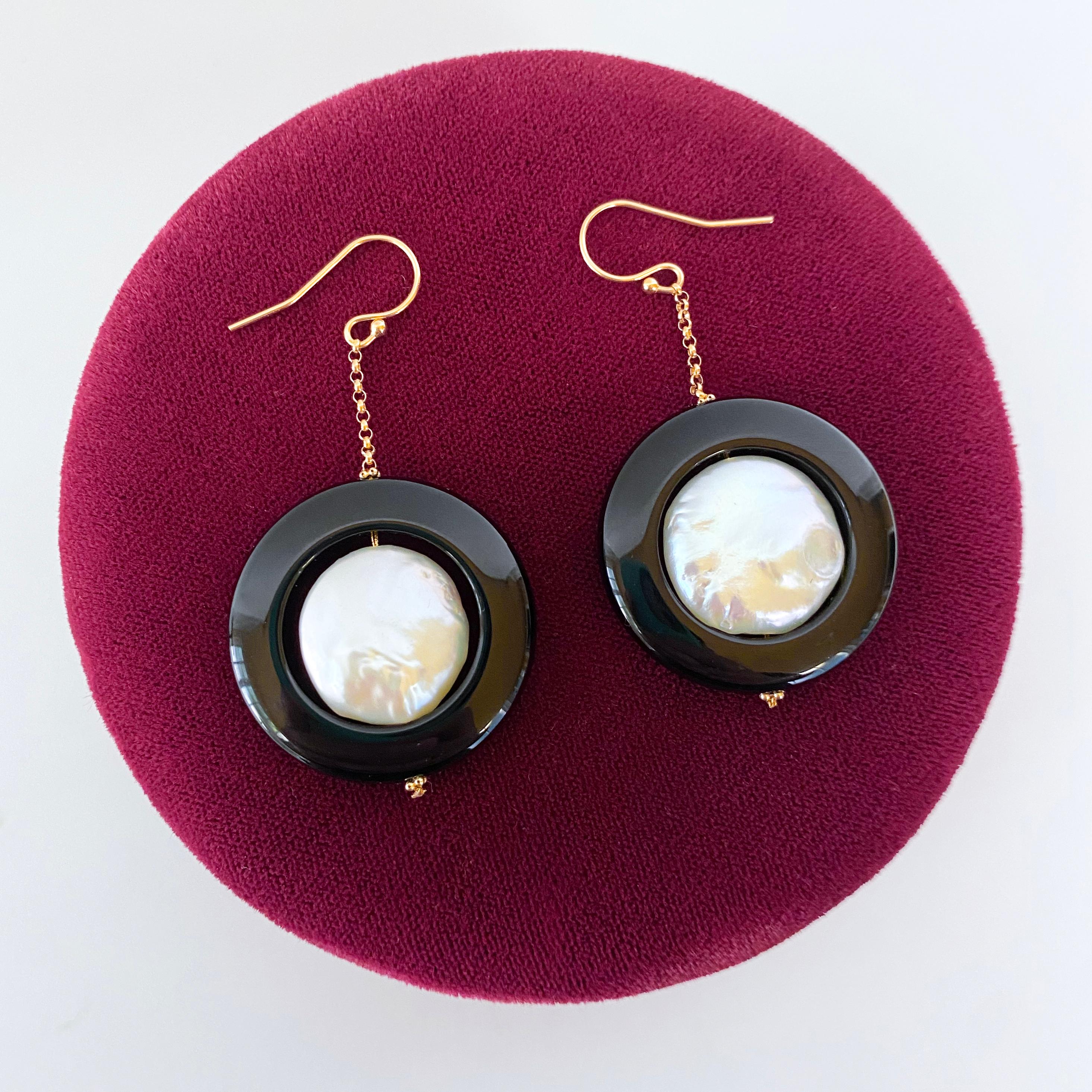 Classic and elegant pair of Earrings by Marina J. This pair features two beautiful Baroque Coin Pearls displaying a multi colored iridescent luster, encapsulated in round Black Onyx. Measuring 2 inches long each, both pairs dangle off solid 14k