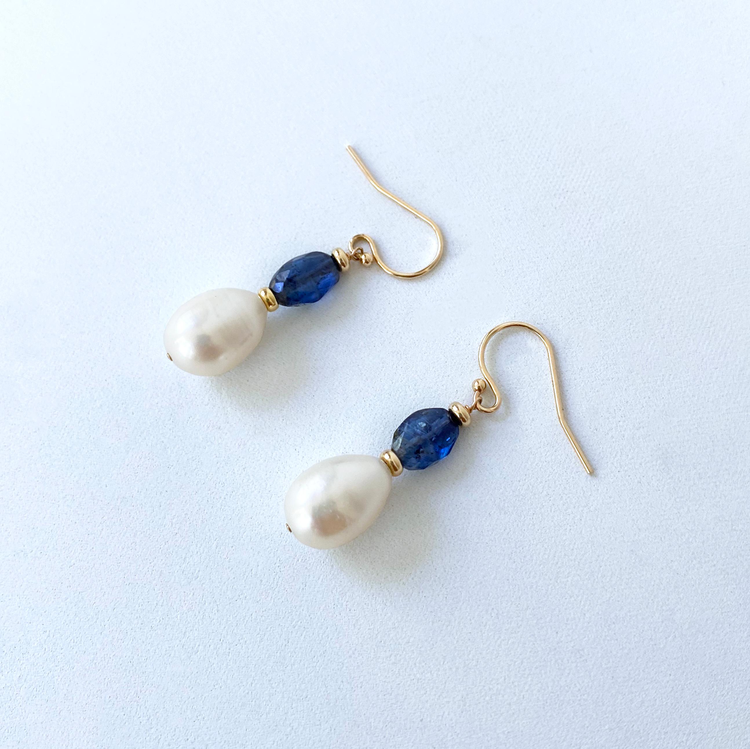 Beau, simple, bleu !

Cette paire est composée de fils et de crochets en or jaune 14k massif, de cyanite bleue facettée et de perles blanches en forme de goutte d'eau. Mesurant 1,5 pouce de long au total, cette paire est parfaite pour une touche de