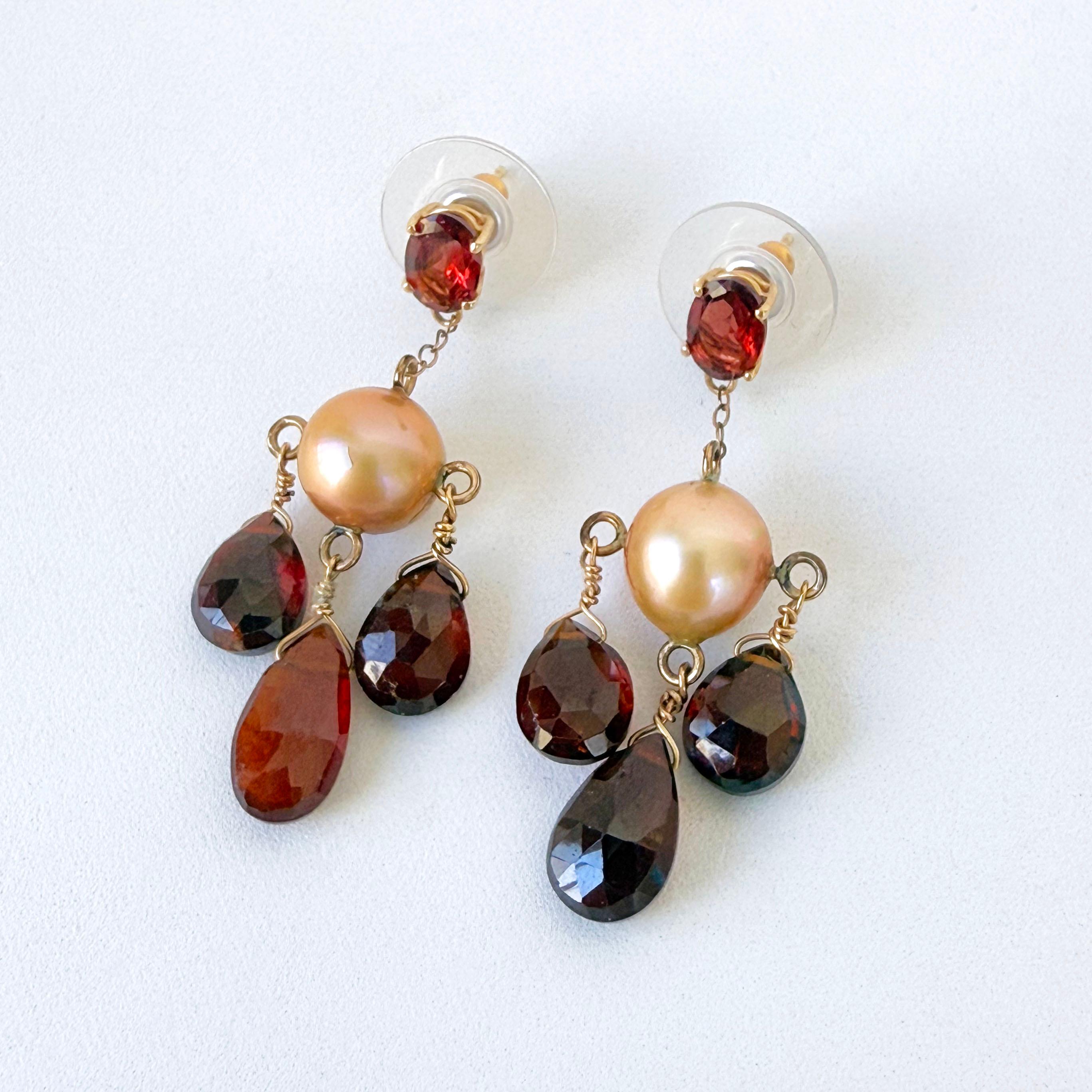 Gorgeous pair of Chandelier Earrings.
This pair features two beautiful Red Garnets bezel set in Solid 14k Yellow Gold as the Studs. From them hang a Solid 14k Yellow Gold Chain that attaches to a round high luster beige Cream from which Faceted