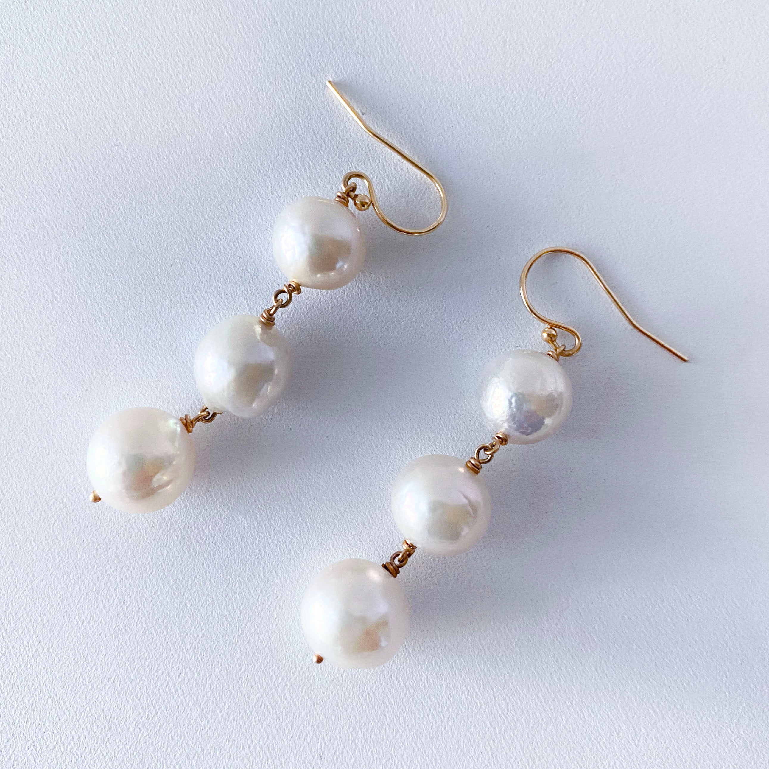 Simple and gorgeous pair of Earrings by Marina J. This pair is made with all Solid 14k Yellow Gold wirings and hooks. Three beautiful white Pearls displaying a soft iridescent luster and texture hang between solid 14k Yellow Gold wiring. The luster