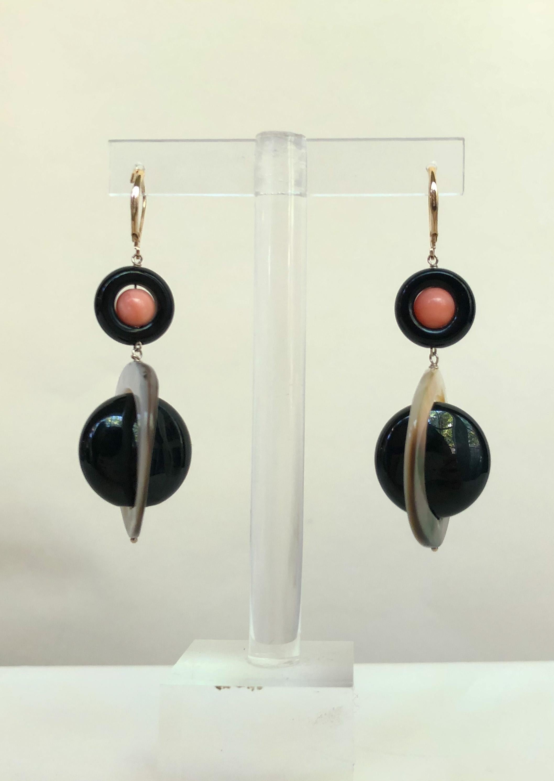 These unique earrings are a bold addition to anyone's jewelry collection. The black onyx provides a striking contrast between the pink coral bead and mother of pearl ring. The earrings are approximately 2 inches long, which allows them to flow and