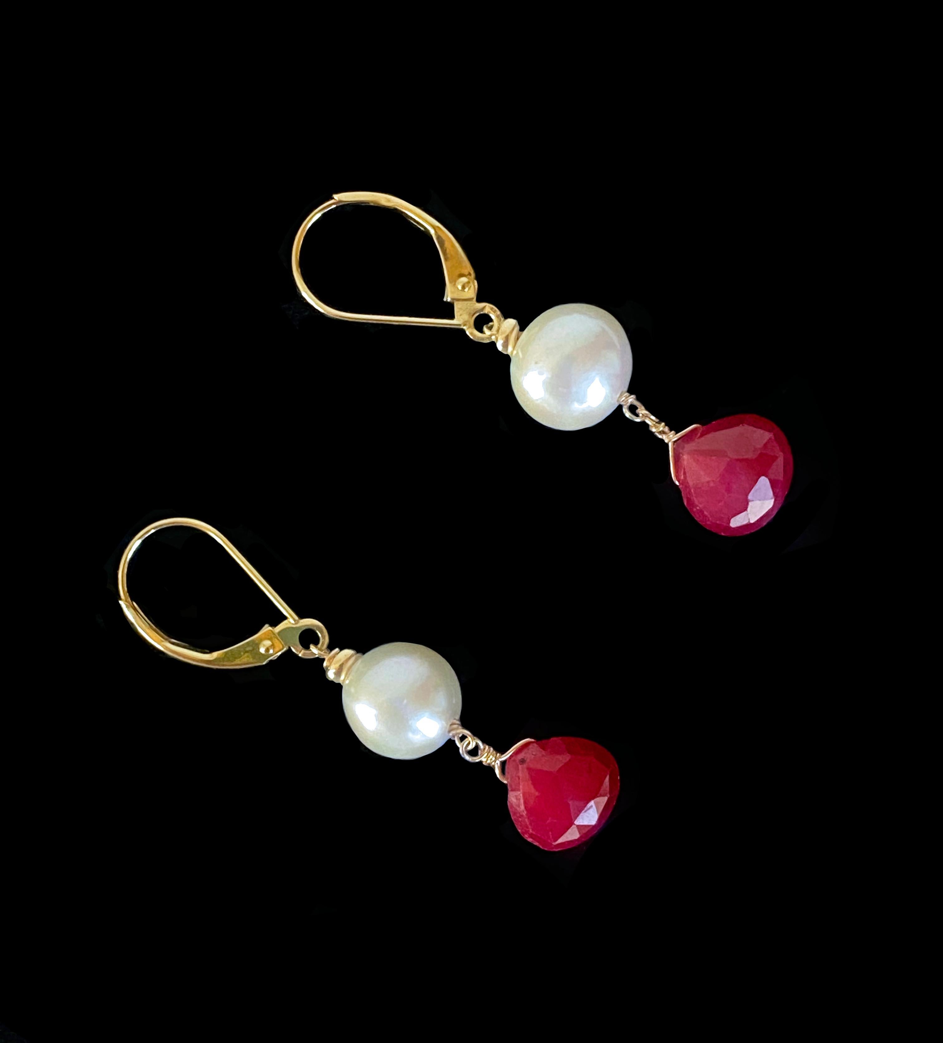Simple yet bold pair of Earrings by Marina J. Measuring 1.5 inches long, these Earrings feature all solid 14k Yellow gold Lever Backs and wiring, from which a round high luster Pearl and faceted Teardrop Ruby hang. The Rubies display a radiant