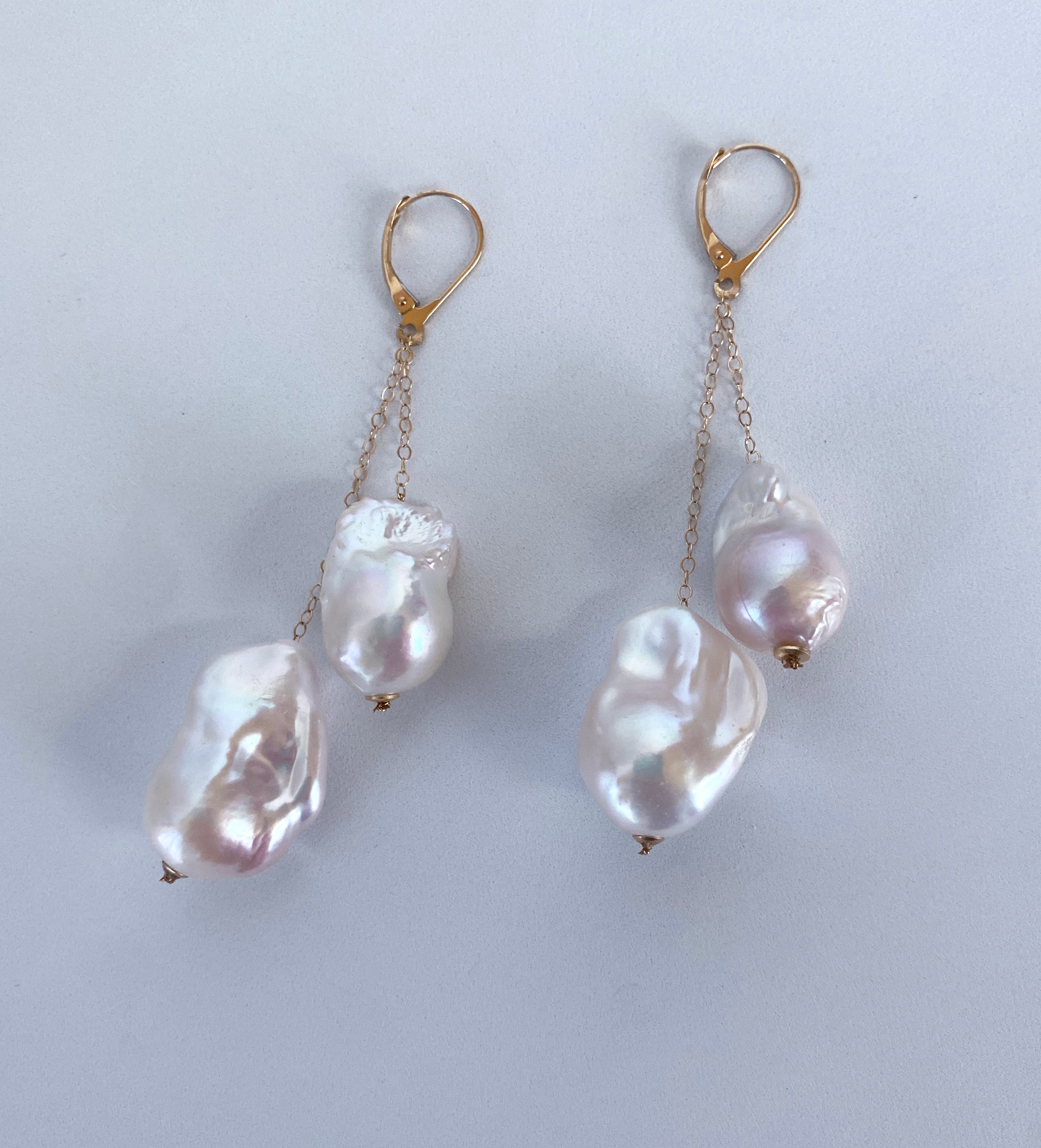 Gorgeous fun pair of Earrings by Marina J. This pair features a total of four cultured white Baroque Pearls displaying a gorgeous multi color iridescent luster. Two Pearls hang from solid 14k Yellow Gold chain on each Earring. Measuring 2.5 inches
