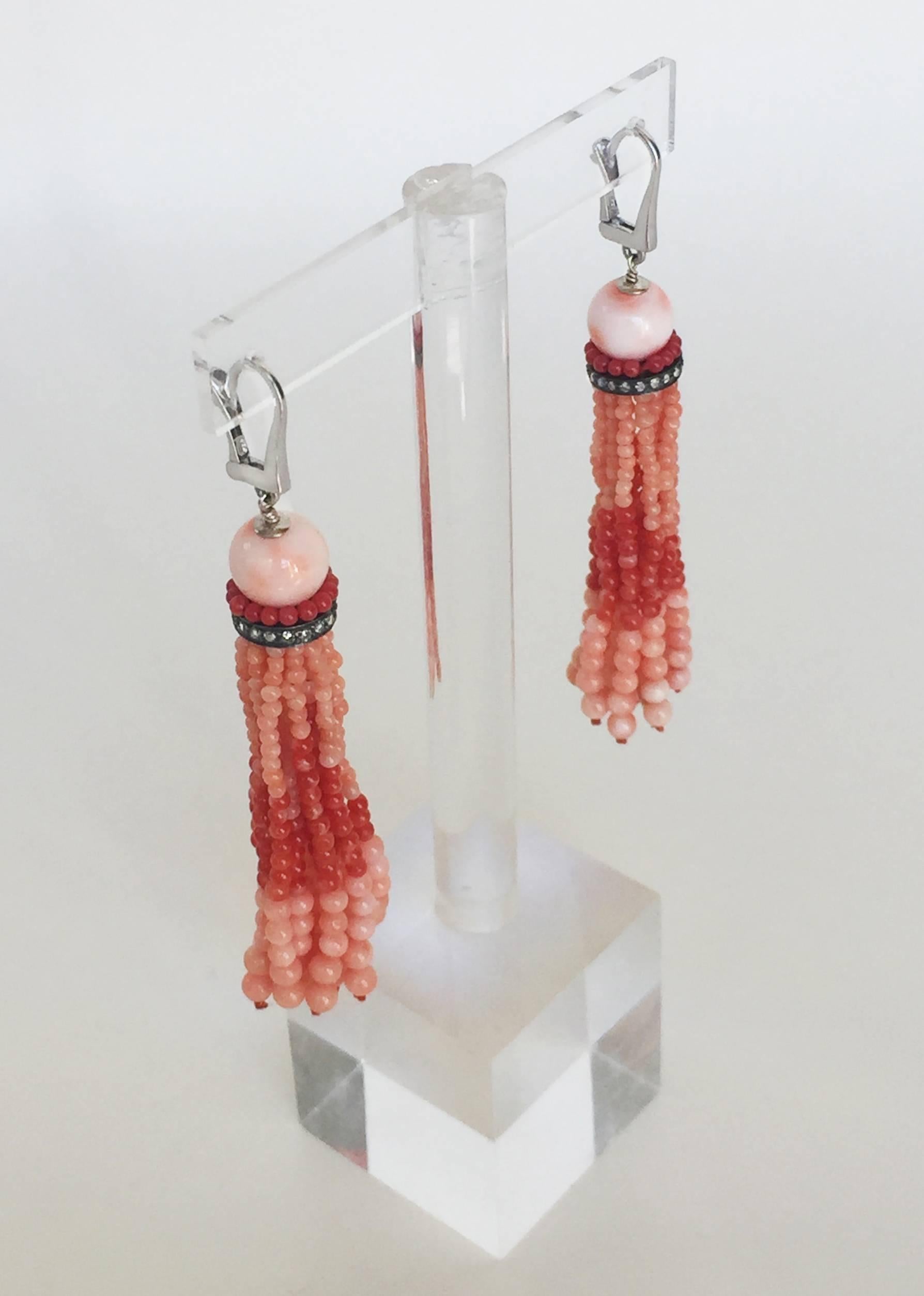 The vibrant tones of pink and red coral makes these tassel earrings a standout piece. A round pink coral bead at the top of the earrings contrasts beautifully with the deep red coral beads and diamond encrusted roundel. The tassel strands are