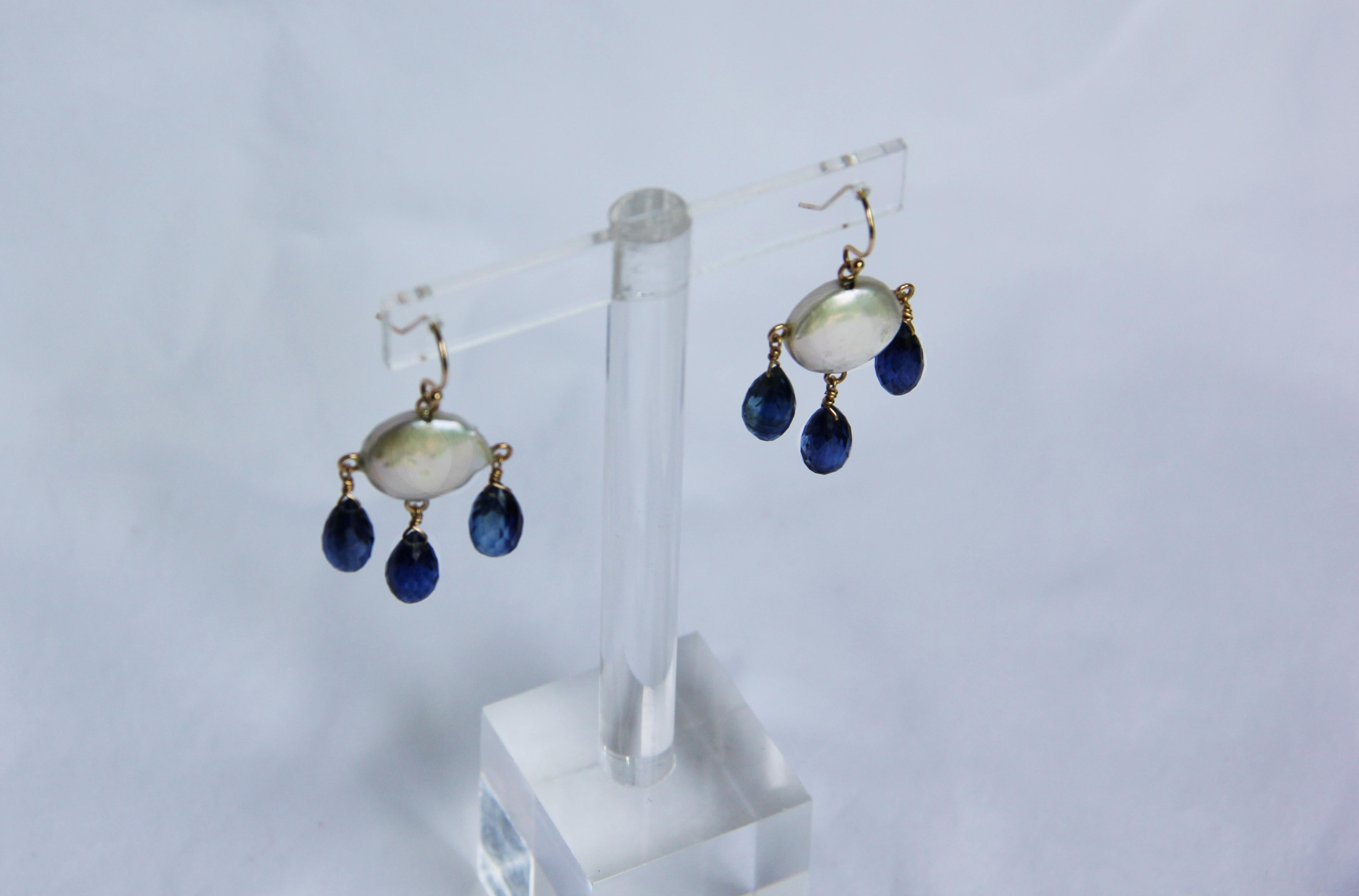 These white coin pearl and kyanite drop earrings with 14k yellow gold hook and findings are strikingly beautiful. The deep royal blue faceted kyanite drops harmoniously hang with a glowing white coin pearl. These earrings are held together with 14k