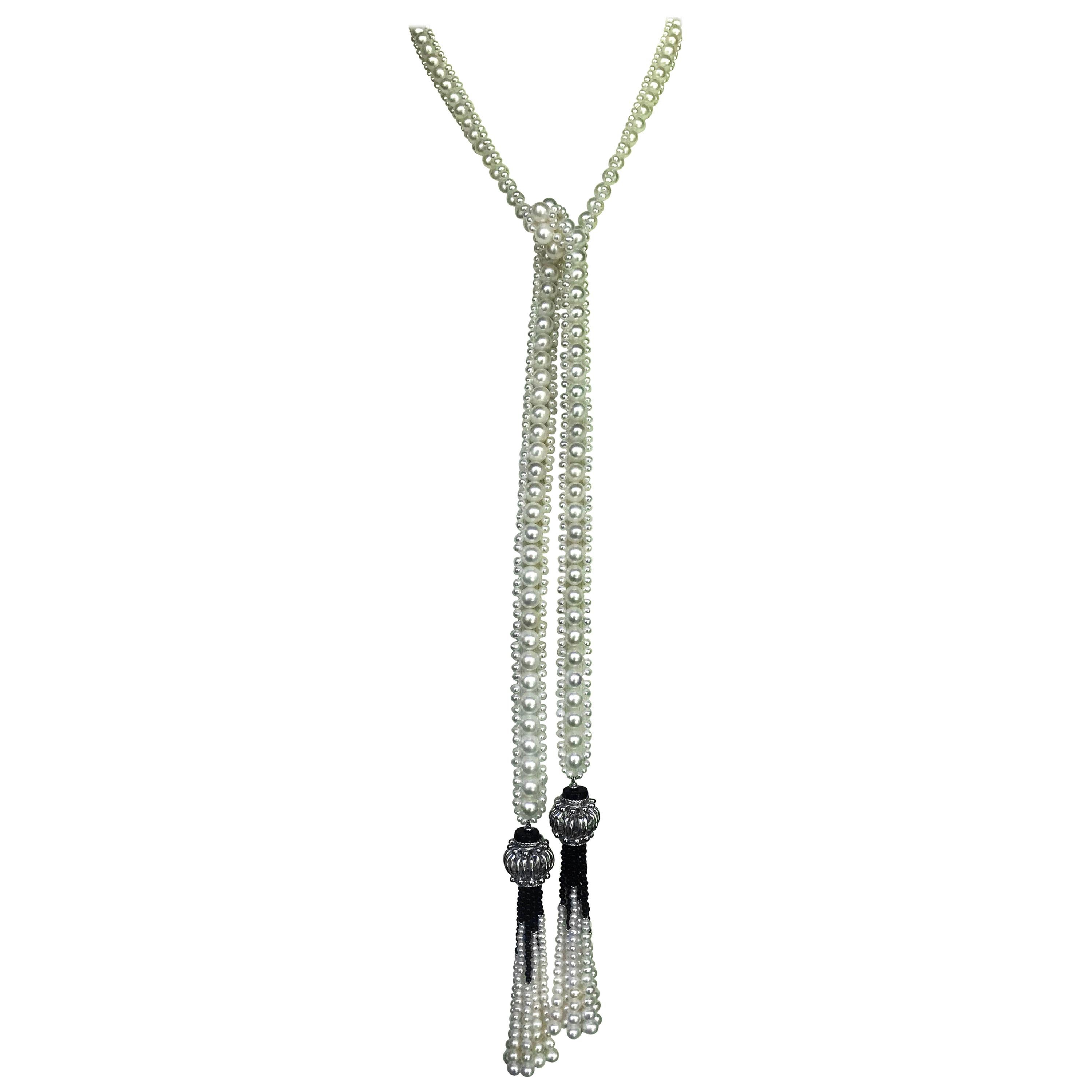 This unique and intricately woven white pearl and onyx sautoir is beautiful, elegant, and versatile. The necklace is made of 2.5mm and 6.5mm white pearls, maintaining a classical look. The tassel strands are made of fine graduated faceted onyx beads