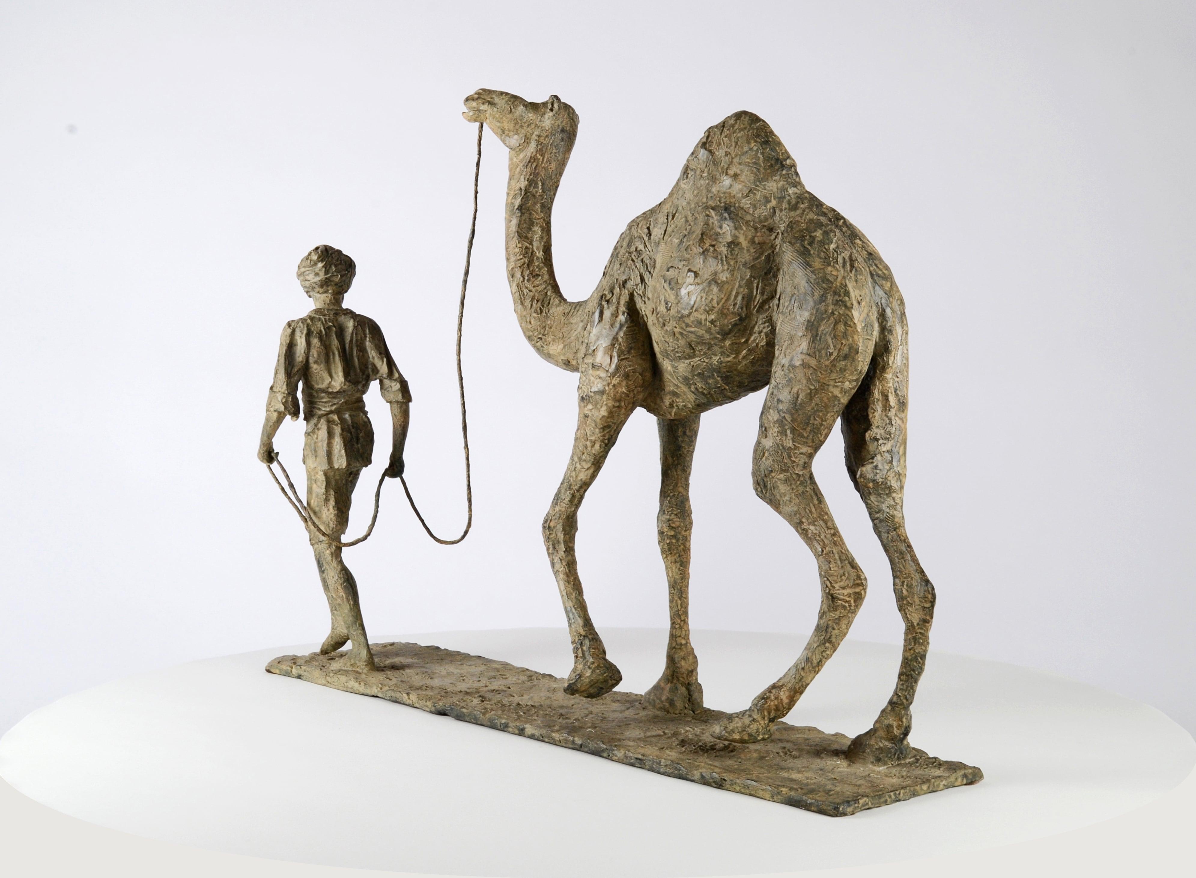 'Au fil des sables', by French contemporary artist Marine de Soos. 
Bronze sculpture a camel led by a man. 56 cm × 75 cm × 17 cm. Limited edition of 8 copies and IV artist’s proofs. Each cast is signed and numbered.
