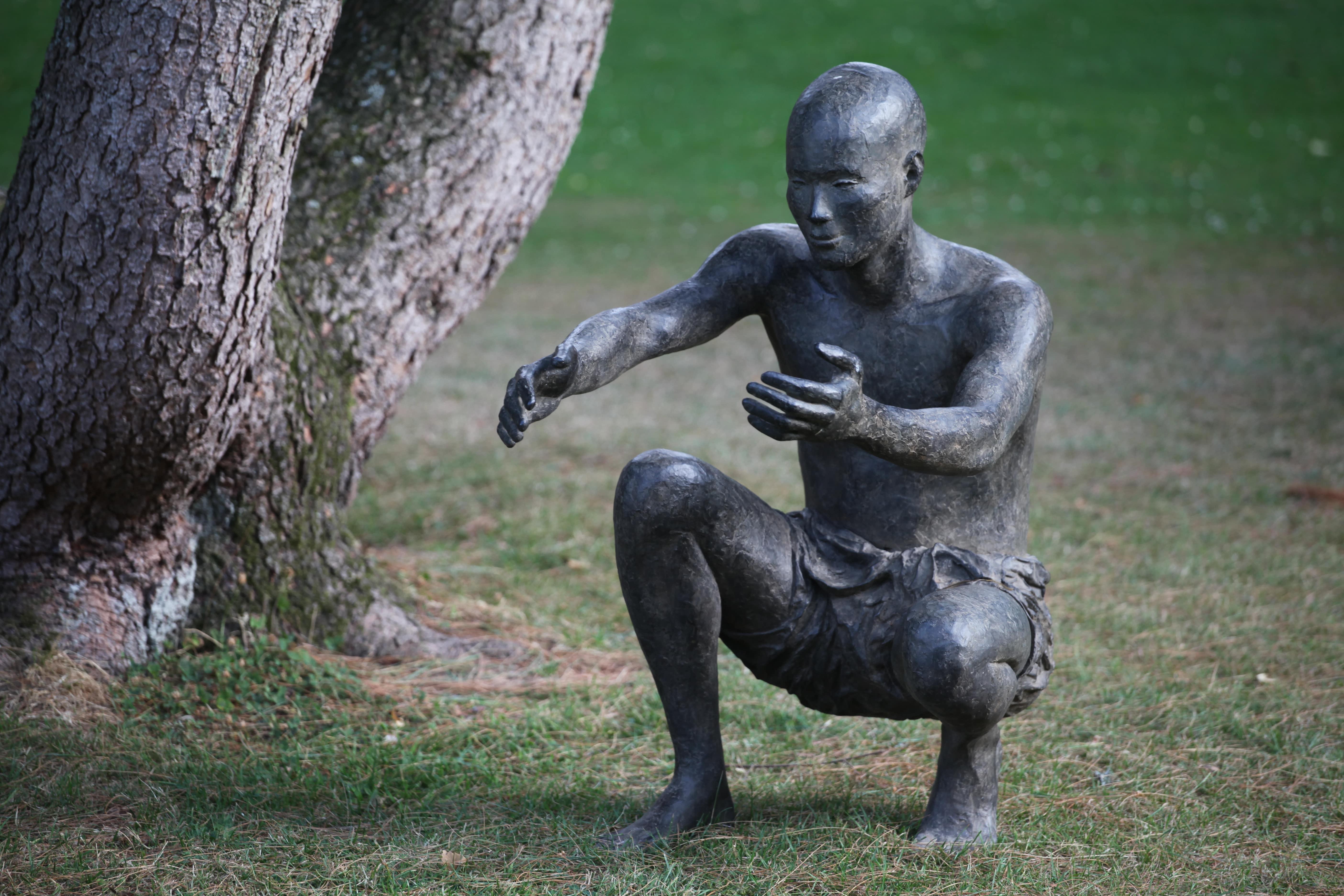 The Welcome by Marine de Soos - Outdoor Bronze Sculpture, Squatting Male Figure