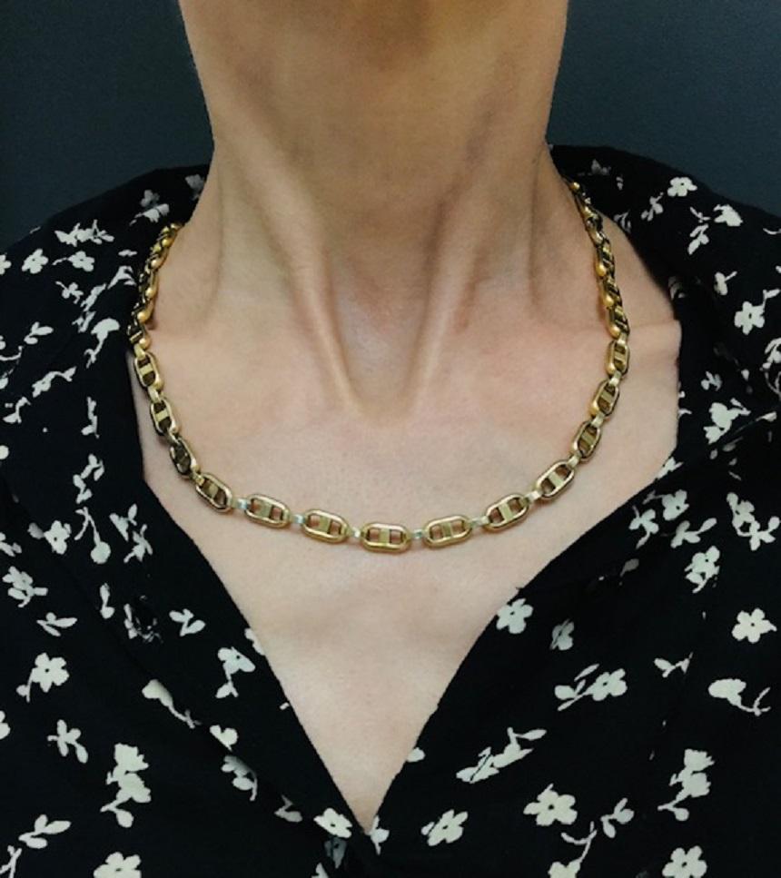 A mariner chain necklace made of 14k gold, circa 1970s. This classic mariner link chain features flat, rectangular links connected by oval gold bands, creating a sleek design. Expertly crafted, this vintage gold necklace drapes elegantly on the
