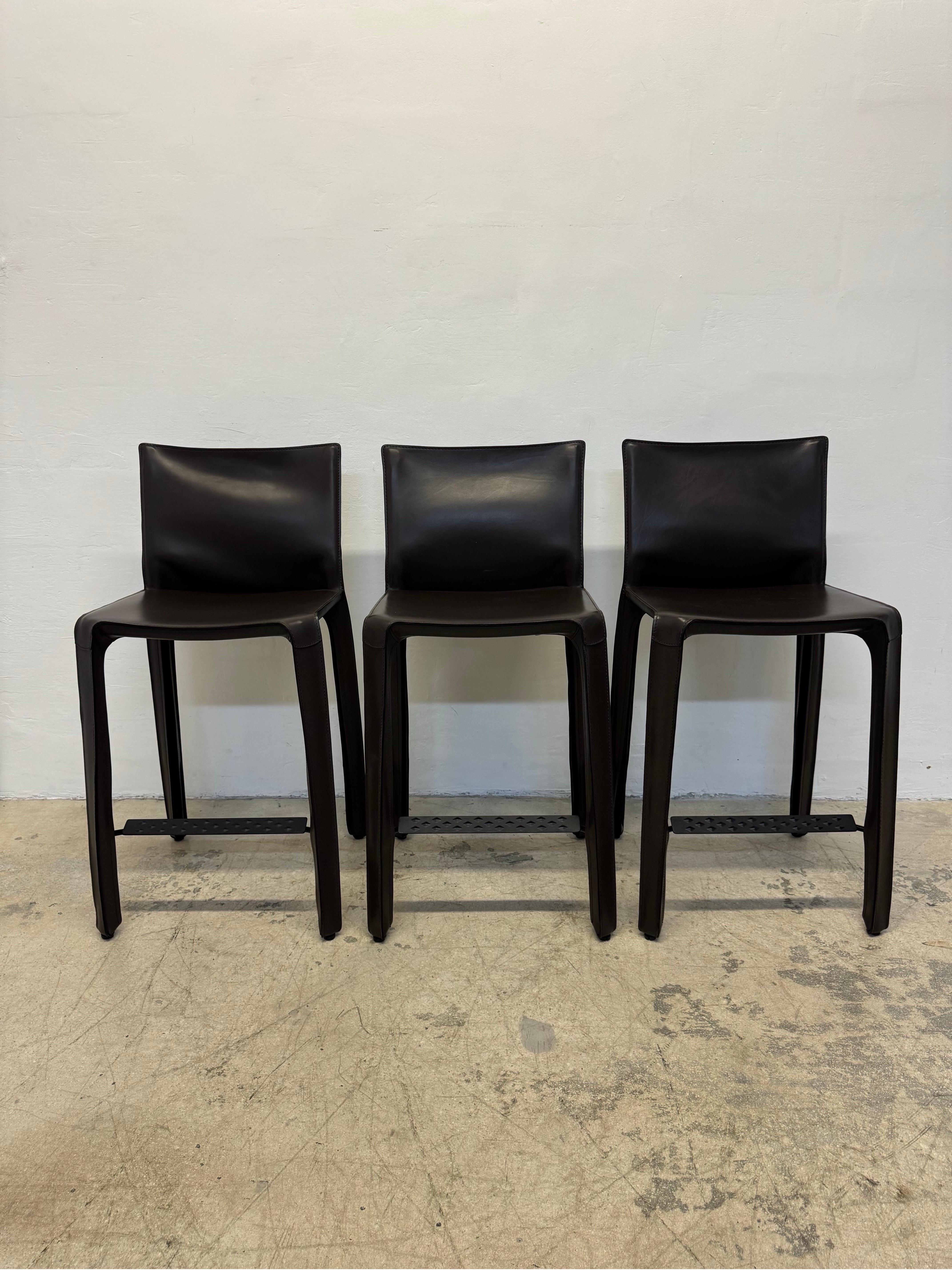 Set of three brown leather counter height stools designed by Mario Bellini for Cassina.

“This was a new kind of chair, constructed totally out of leather, much cloned since then.” Thus Mario Bellini describes Cab, a best-seller that he designed in