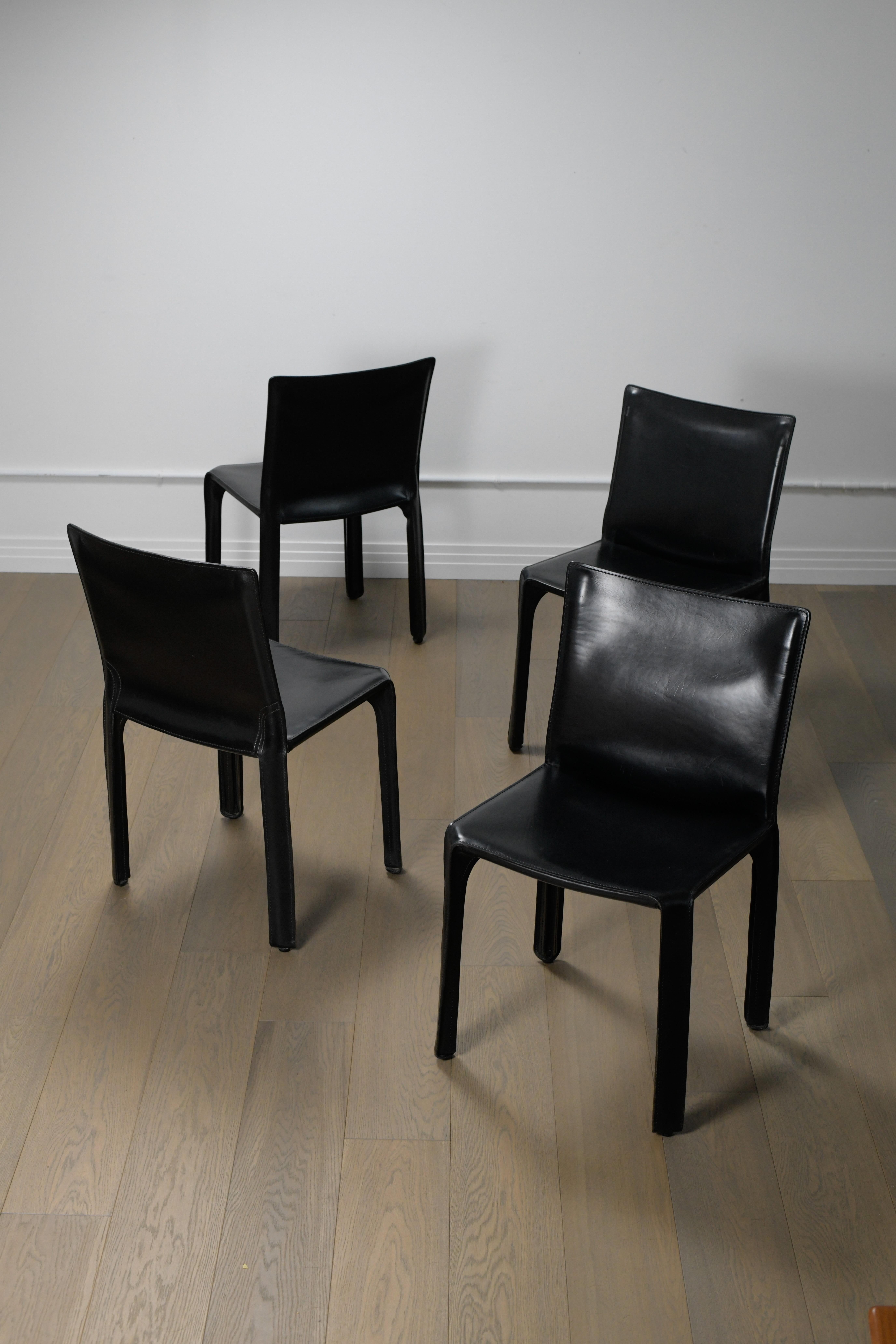 Ensemble de quatre chaises Cab Mario Bellini des années 1970 en cuir noir par Cassina. Ces belles chaises de salle à manger sont en bon état avec une belle patine correspondant à leur âge. Il y a quelques petites égratignures sur les sièges et le