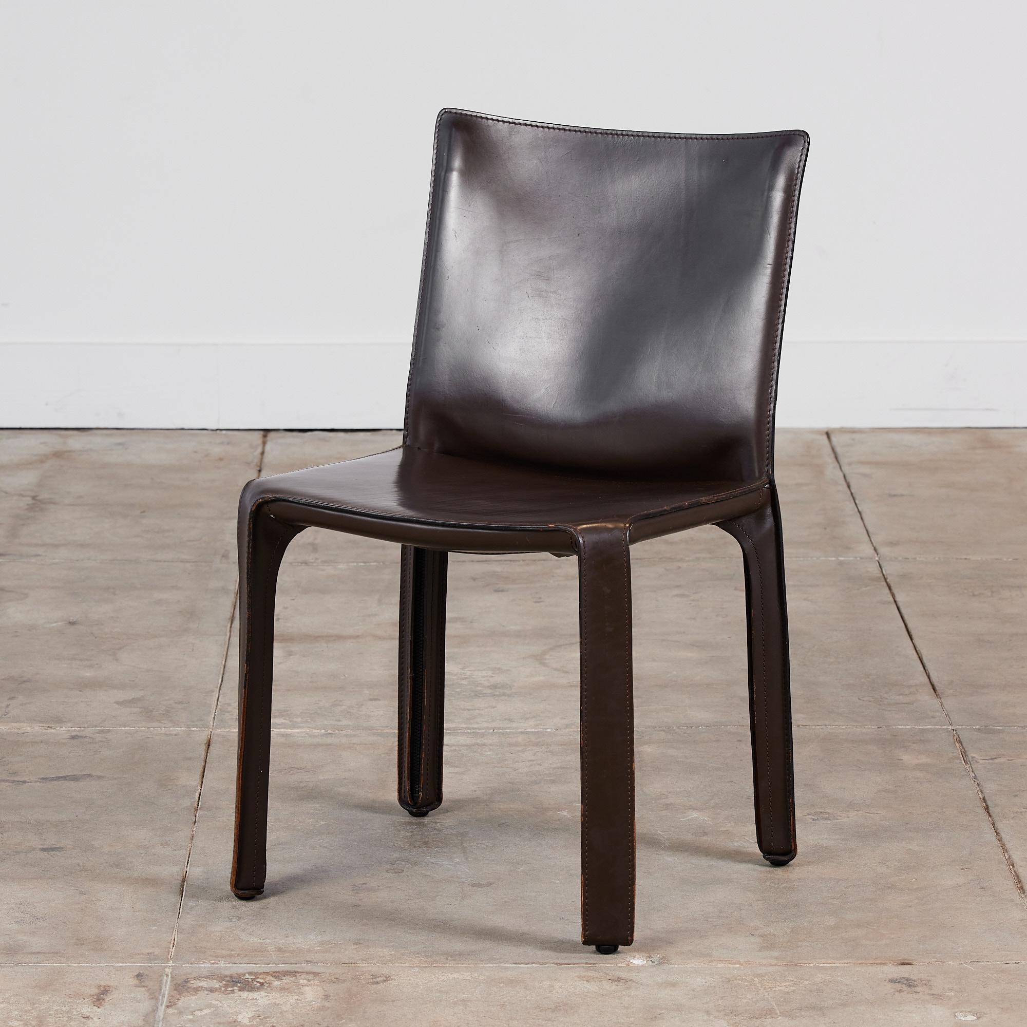 This iconic design by Mario Bellini for Cassina c.1970s, Italy, features the original deep brown saddle leather which is wrapped atop a steel frame. The back legs feature a black zippered detail. The bottom of the chairs are marked - Cassina.

One