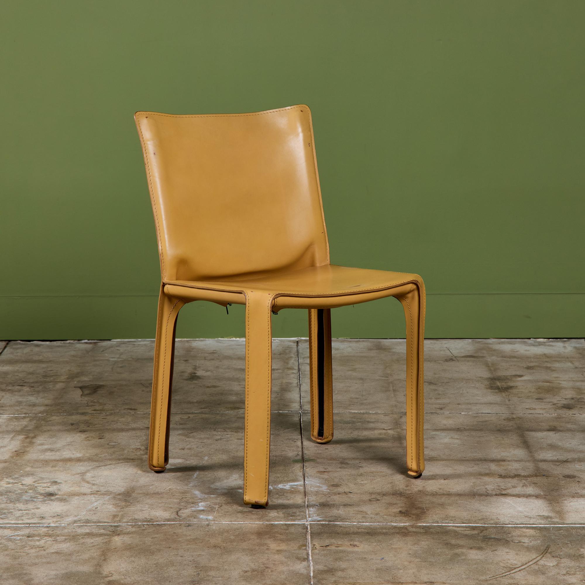 This iconic design by Mario Bellini for Cassina c.1970s, Italy, features the original natural toned saddle leather which is wrapped atop a steel frame. The back of each leg features a black zippered detail. The bottom of the chairs are marked -