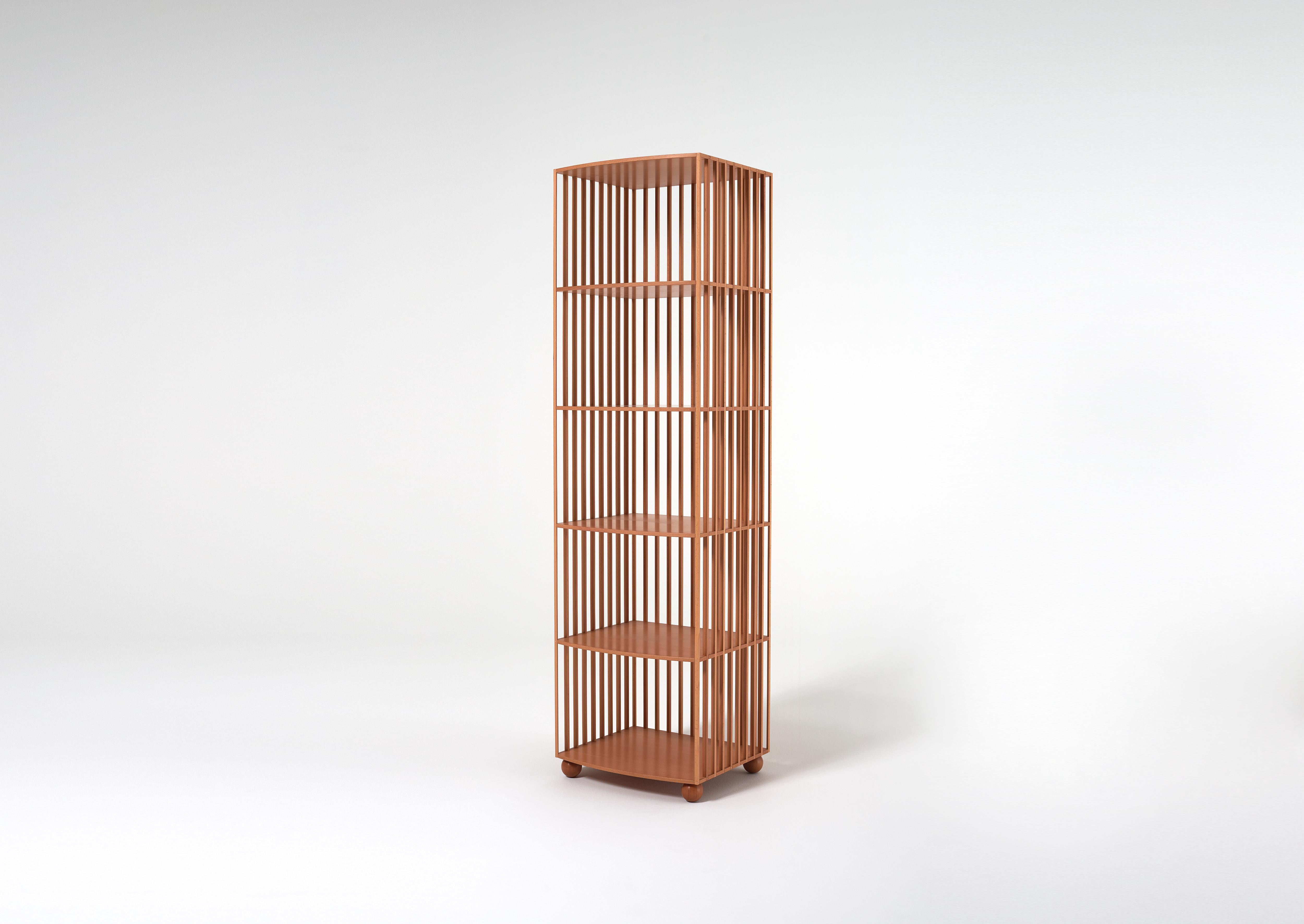 A bookcase designed for the centre of a room, made of a lining of solid-wood baguettes that are rounded off and joined to countertops through invisible joints. The result has impressive structural strength while looking light and airy. With