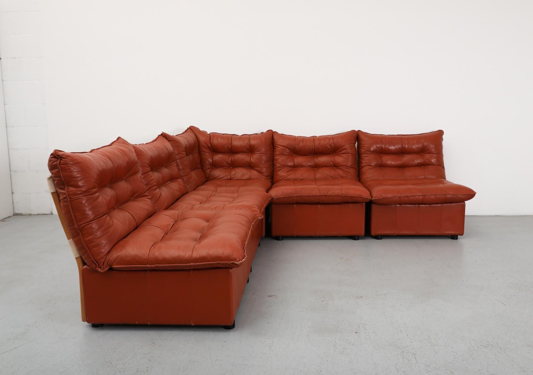 Bellissimo divano componibile in pelle color mattone in stile B&B Italia con spessi cuscini trapuntati montati su basi rivestite in pelle con cinghie in tela e supporti in legno di faggio a vista.
Questo set comprende quattro unità diritte e un