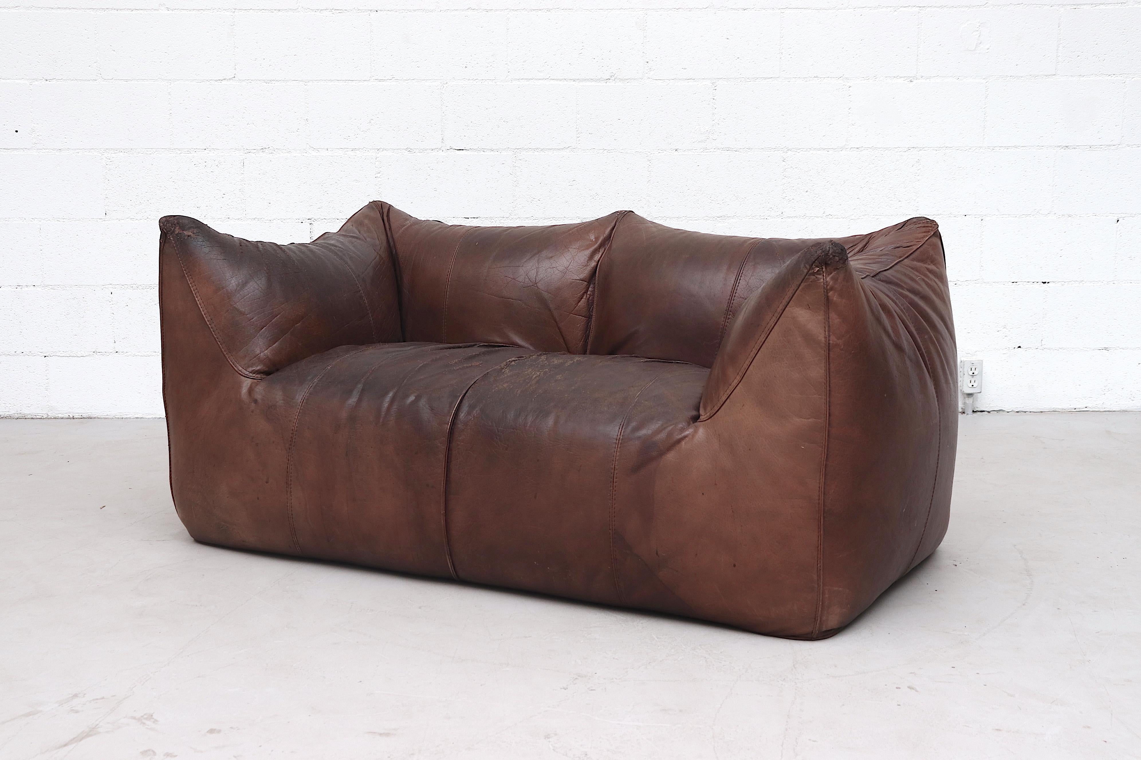 Mario Bellini 'Le Bambole' leather love seat in well worn brown leather. Very worn and used condition with heavy patina and extreme wear consistent with a lot of use. Shows extreme use and has some visible repairs to the top arm corner. As is.