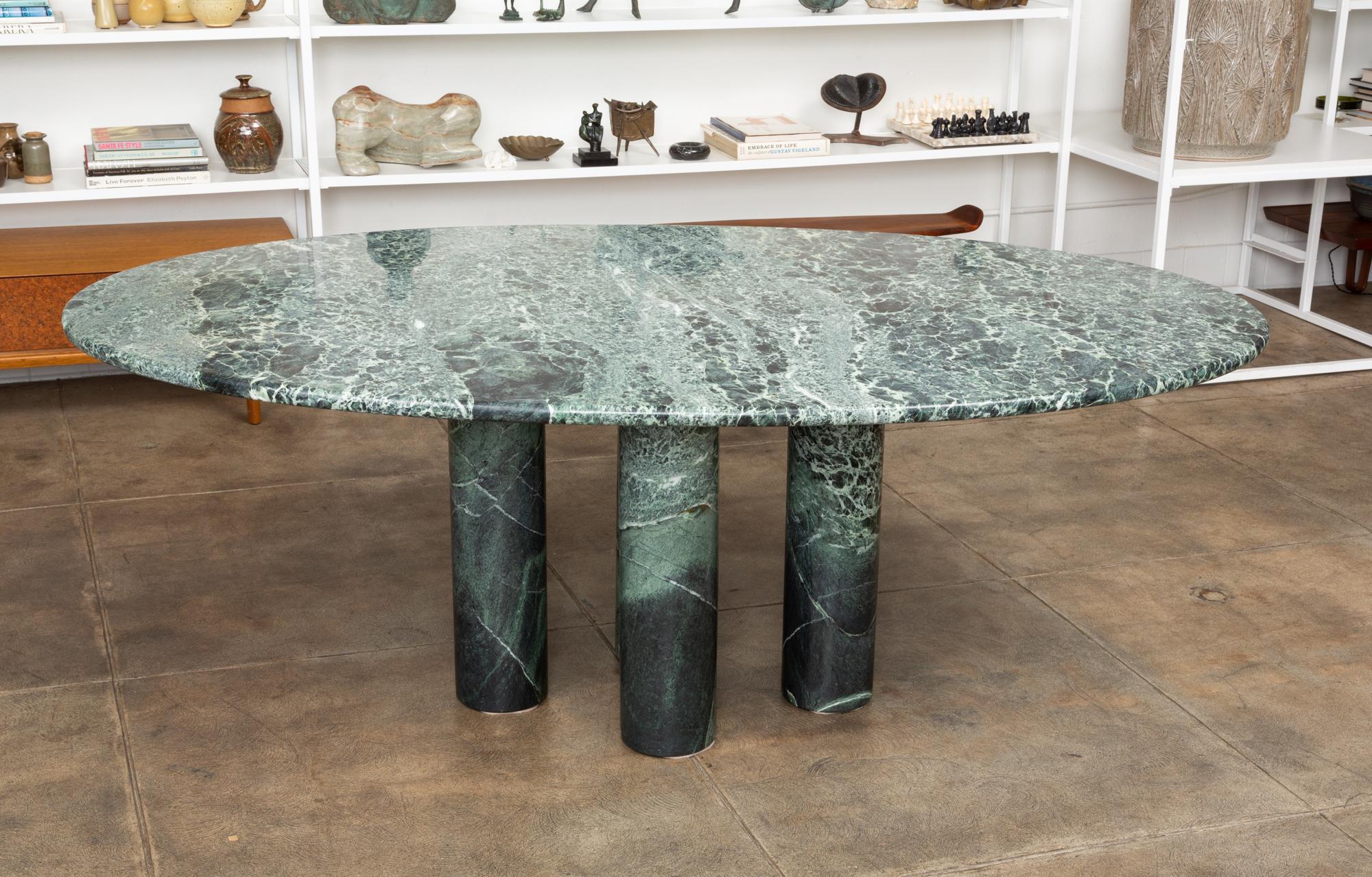 'Il Colonnato' oval dining table in green marble by Mario Bellini for Cassina. The table features an oval horse track top in green marble with distinct white veining. The upper portion of the four thick column legs also has the vibrant white veining