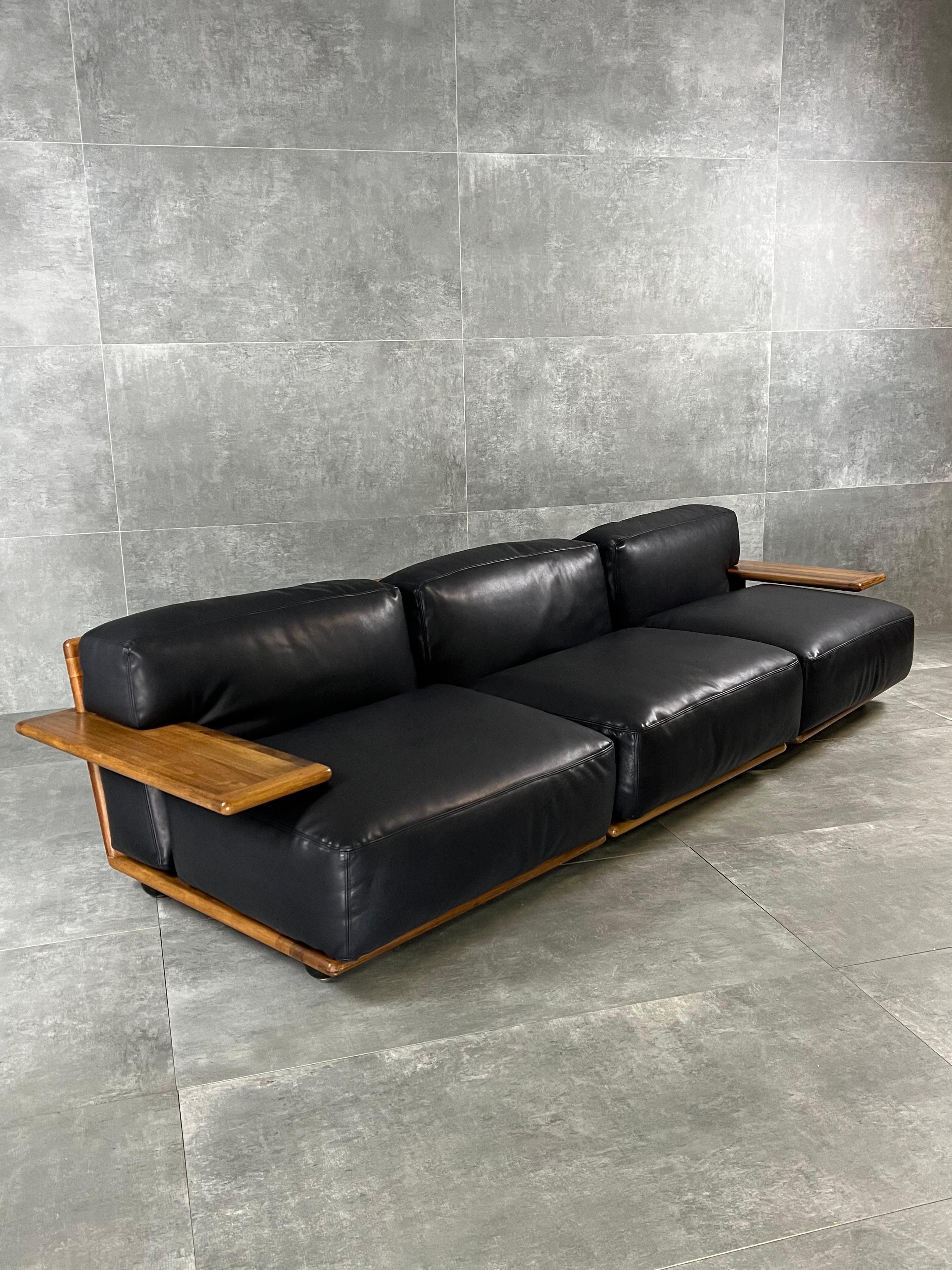 Stunning modular sofa designed by Mario Bellini and manufactured by Cassina in Italy during 1970s. It features a wooden structure with high comfort cushions reupholstered in black leather. Original manufacturing label on the bottom. It shows few