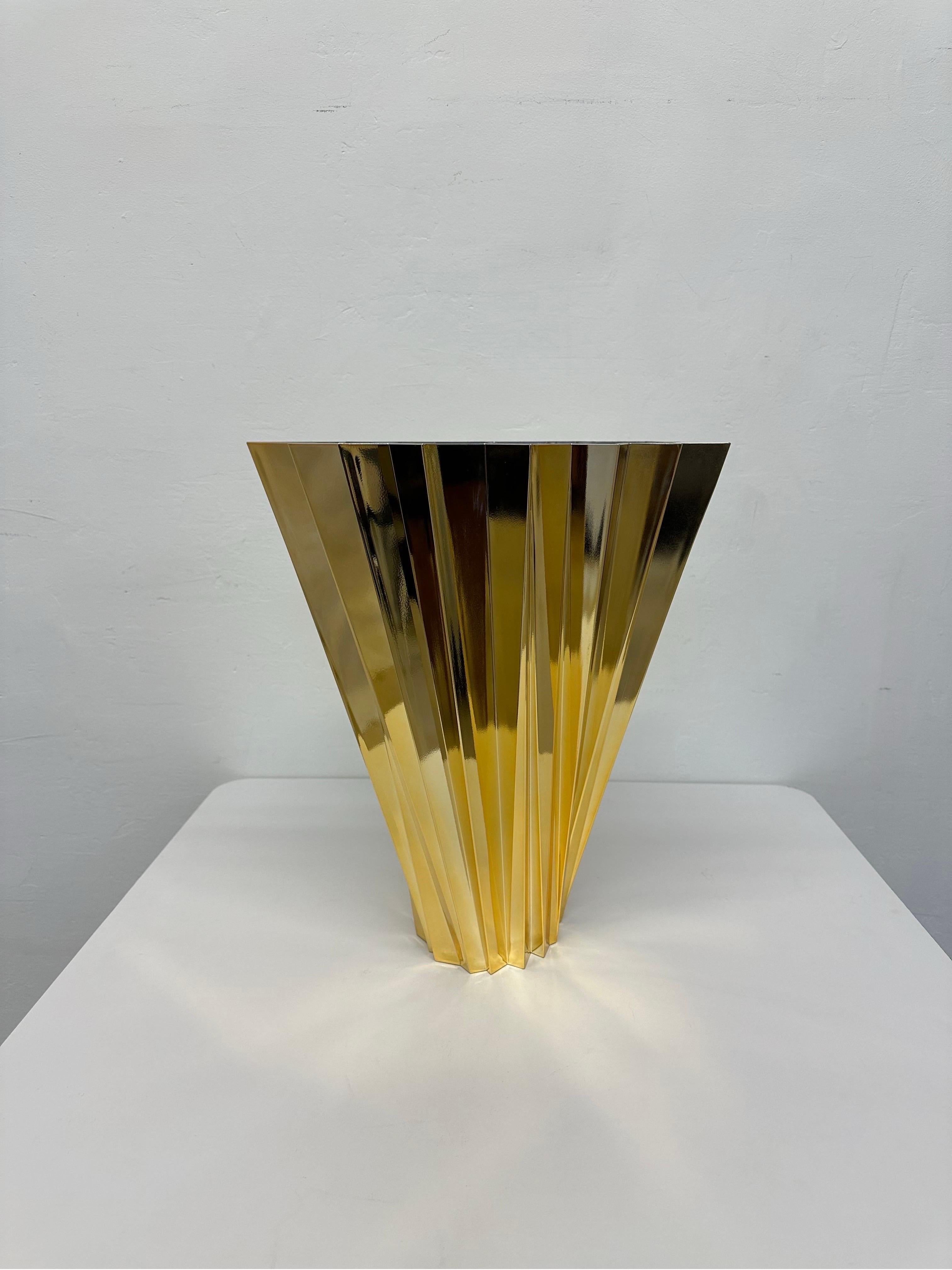 Gold Shanghai vase designed by Mario Bellini for Kartell.

A multi-faceted vase widening from the base to the top in a swirling motion. Shanghai is like refracted light radiating from prism-like crystals with an alternating play of flashes and