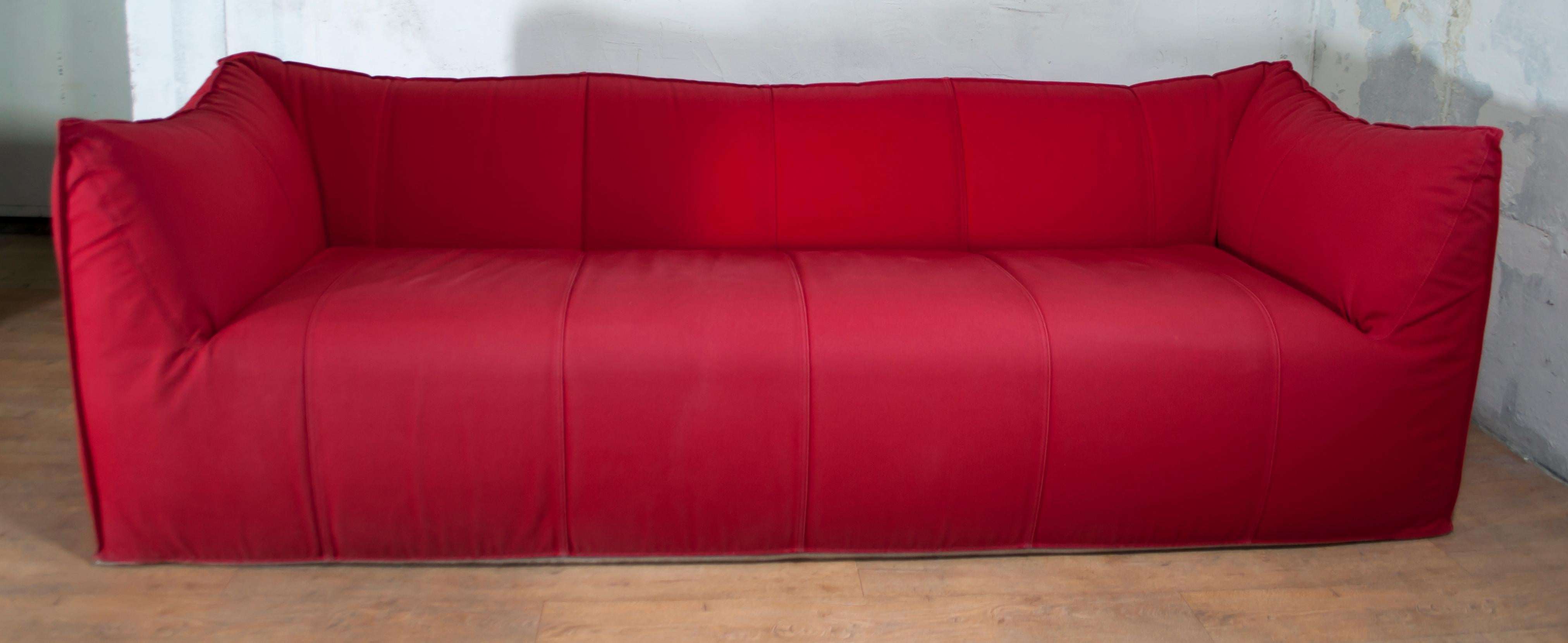 Mario Bellini designed Le Bambole for B&B Italia in 1972, armchairs and sofas shaped in their entirety as large cushions. Combining extraordinary comfort and style, this Tribambola sofa and the Pouf are upholstered in a vibrant red canvas, which is