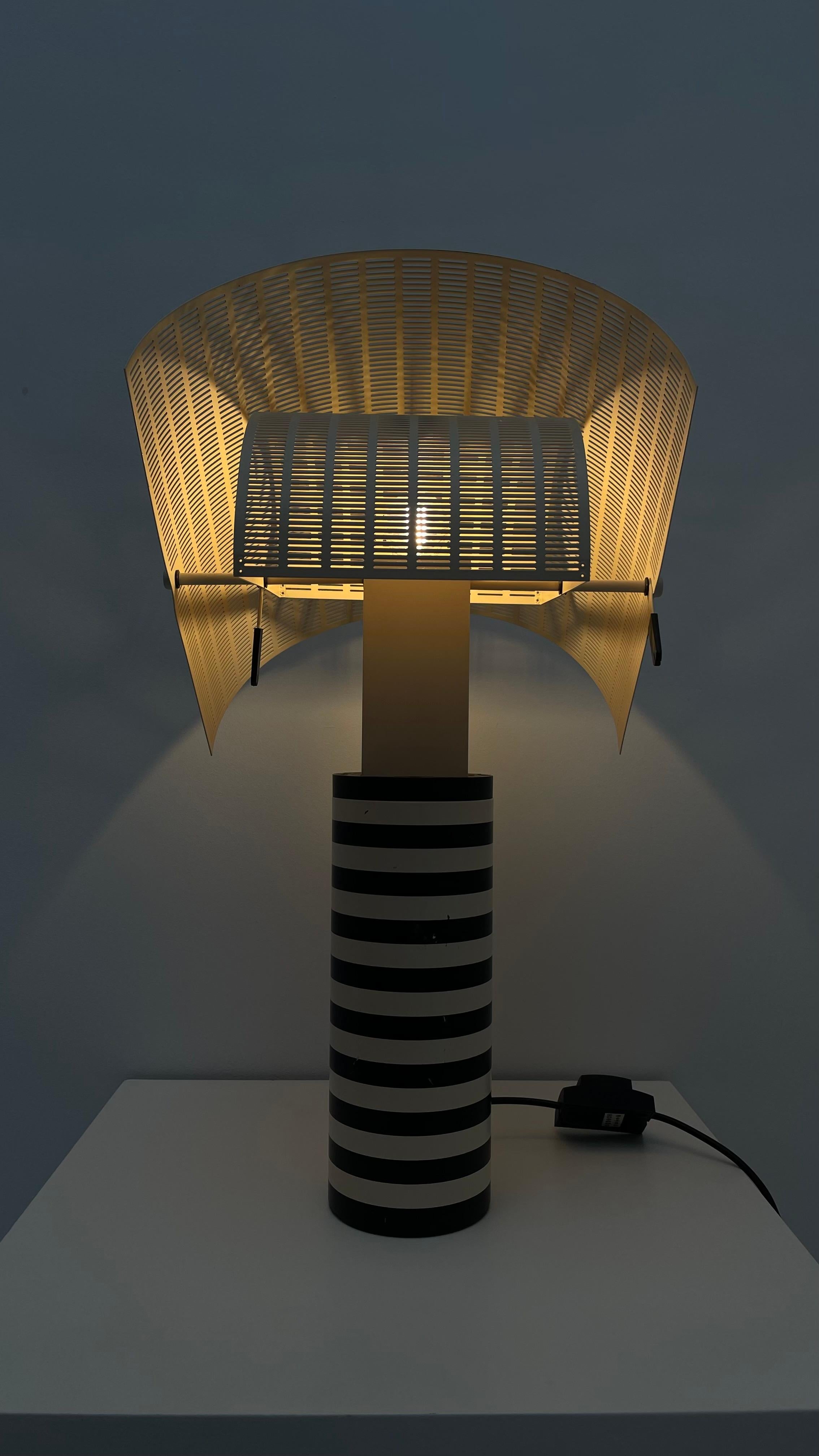 For Mario Botta, the Shogun table lamp represents a person, whether it's turned on or off. Its adjustable double-layered shade creates different shadows through the perforated steel plates, while its black-and-white striped body evokes the