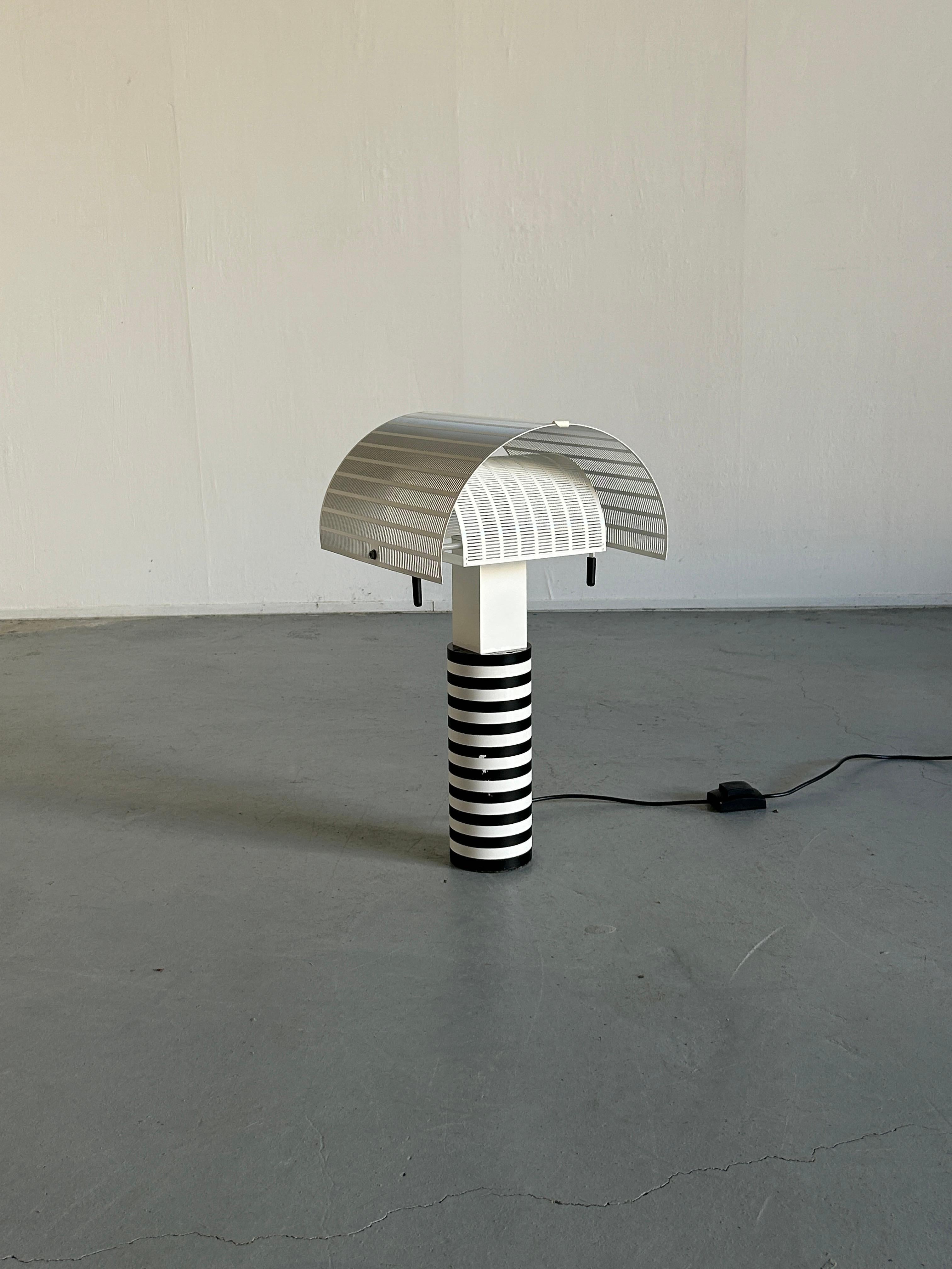 Mario Botta for Artemide, 'Shogun' table lamp, metal, Italy, 1986.
Late 1990s or early 2000s production,

Mario Botta referred to lamps as “people”. He said “Shogun is a person. He has a head, body and feet, plus he has a navel.” 
The designer is