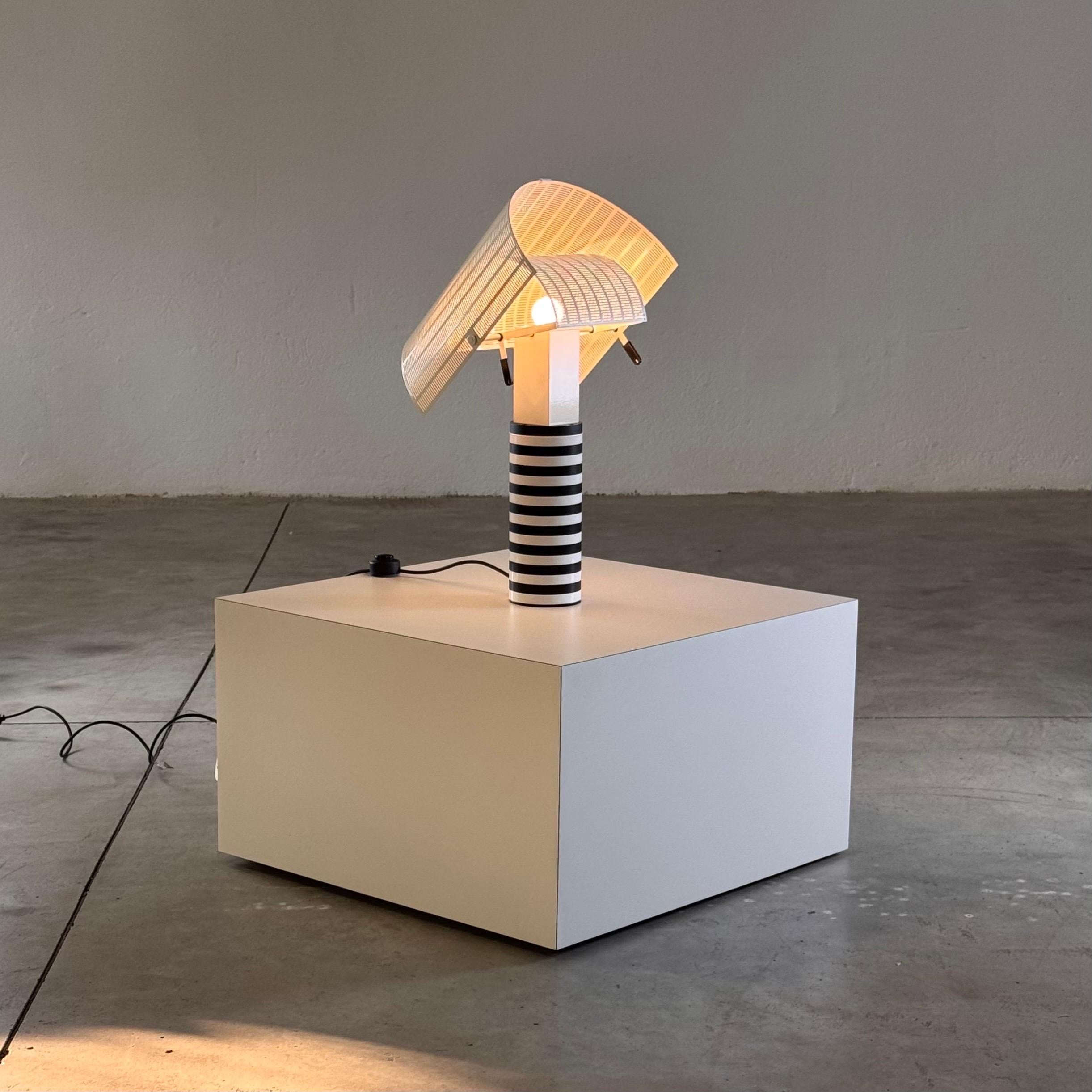 The 'Shogun' table lamp, designed by Mario Botta for Artemide in 1986, embodies the visionary architect's signature style of geometric precision and functional artistry. Crafted in Italy, this sculptural piece seamlessly combines form and function,