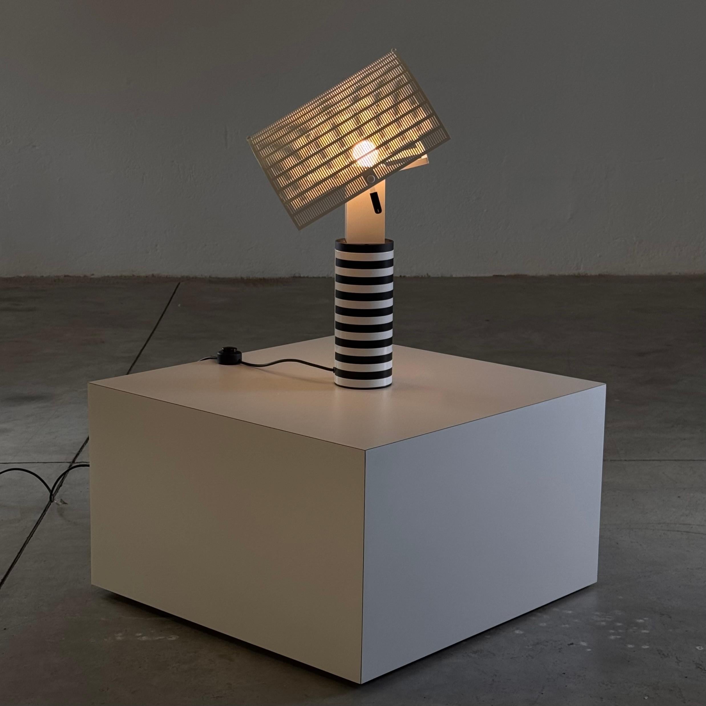 The 'Shogun' table lamp, designed by Mario Botta for Artemide in 1986, embodies the visionary architect's signature style of geometric precision and functional artistry. Crafted in Italy, this sculptural piece seamlessly combines form and function,