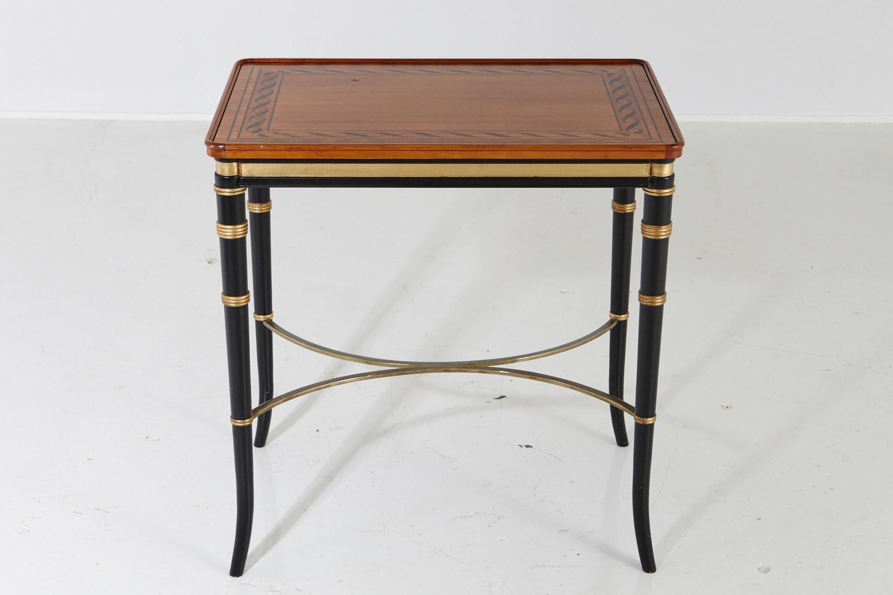 Beautiful eye-catching Regency style end table with paint decorated top and ebonized apron and legs with gilt rings, splayed feet, and brass reverse 