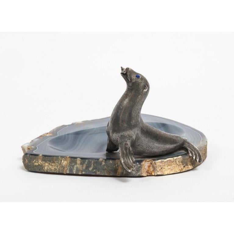 Mario Buccellati, A rare ashtray or centerpeice with a silver seated seal eating a fish with Lapis Lazuli eyes, mounted on blue agate.  Marked Buccellati, Made in Italy and 800.  The meaning of blue agate is calmness. Blue agate stone is known as a