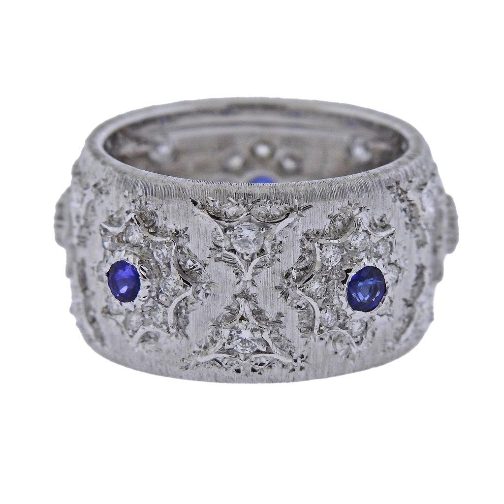 18k white gold wide band ring, designed by Mario Buccellati, set with blue sapphires and approx. 0.60ctw in H/VS-Si diamonds. Comes with COA. Ring size - 7, ring is 12mm wide and weighs 9.6 grams. 