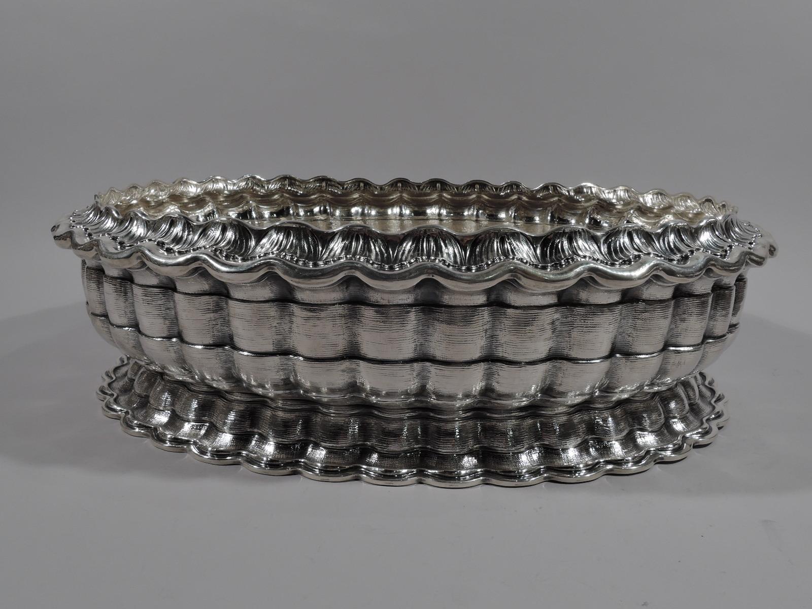 Modern Classical sterling silver centerpiece bowl. Made by Mario Buccellati in Milan. Oval. Sides comprise bands with ribbon lobing and dense horizontal striation. Foot spread and same. Turned down rim with chased acanthus leaf border. Scalloped