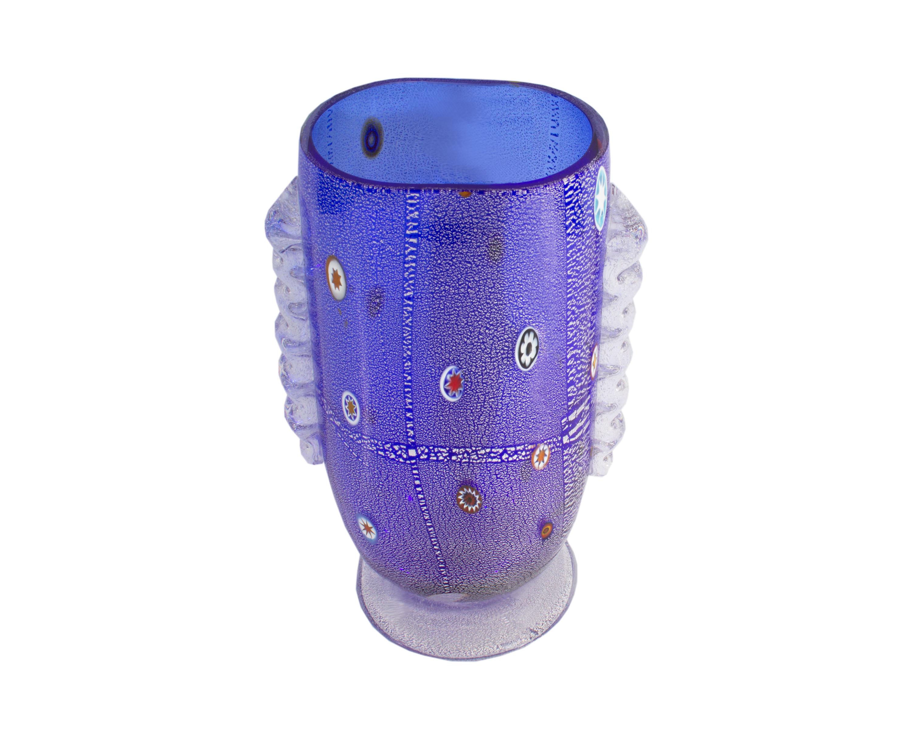 A Murano art glass vase by the Italian glass artist Mario Gambaro (born 1941). Made in Italy and Ssigned “Gambaro M” to the underside, this tall cobalt blue vase sits on a circular base. Ruffled glass designs have been affixed to the sides of the