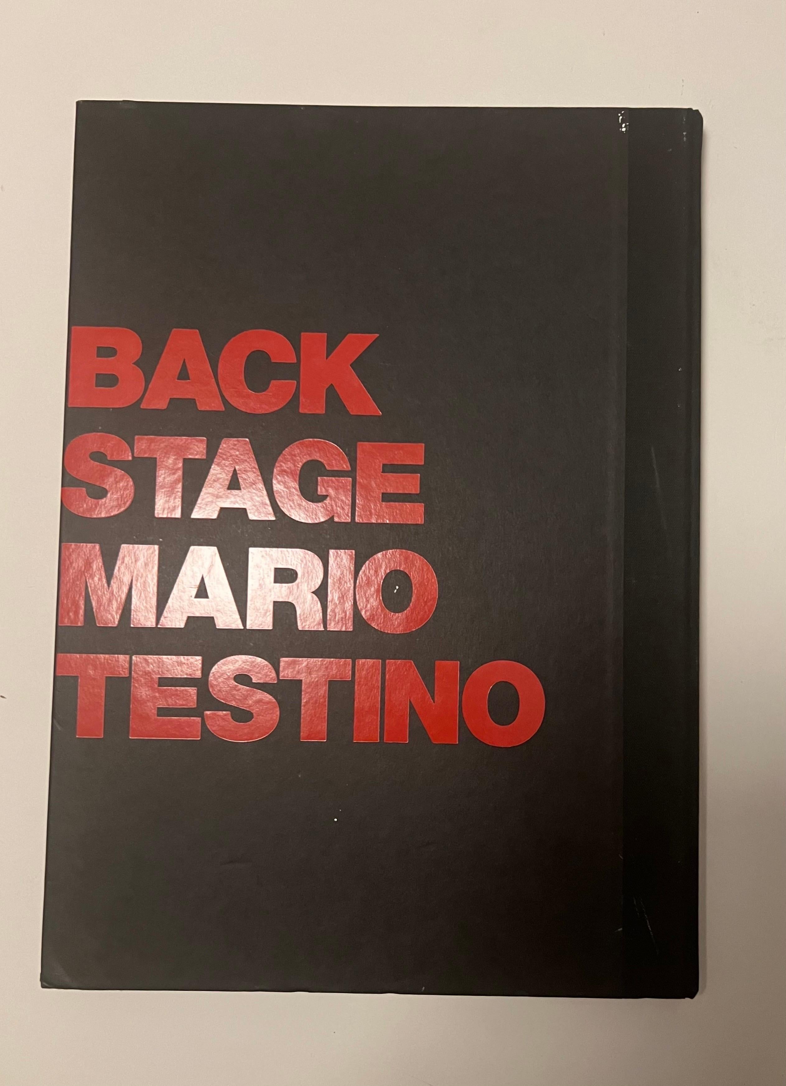 The oversize first edition hardcover book, Front Row/Backstage, by photographer Mario Testino.

Published in 1999, Front Row/Backstage captures the excitement and drama of the international shows in Paris, London and Milan. In this book, Testino has