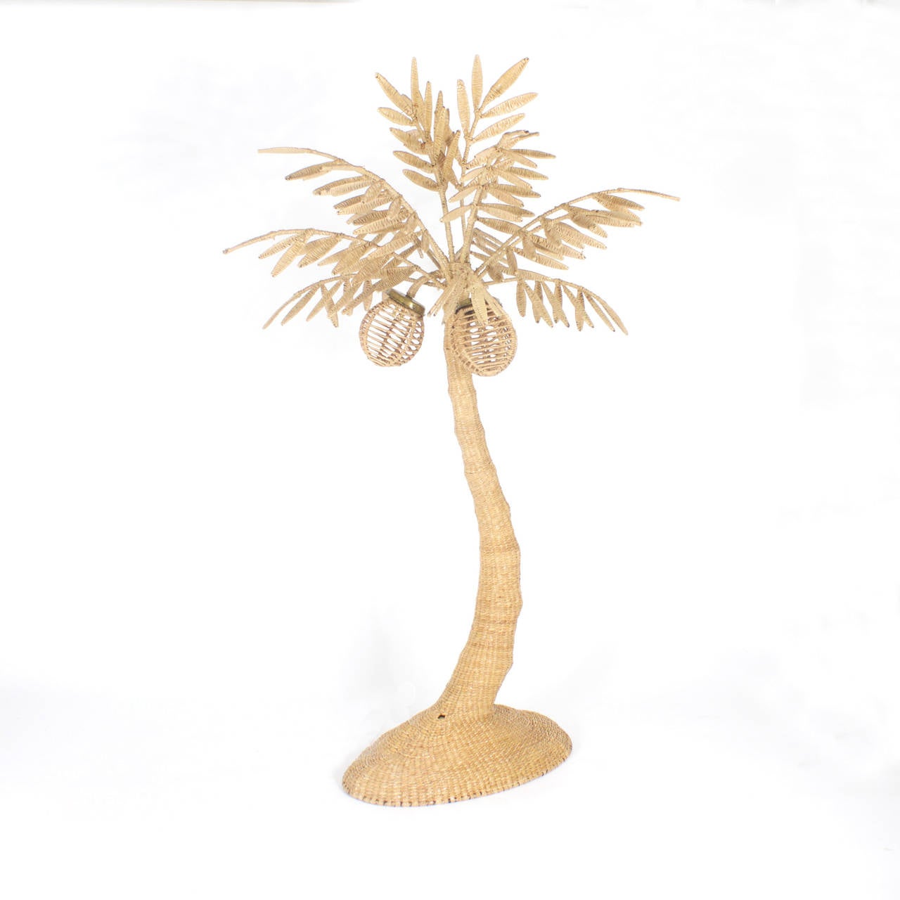 Folky Mario Torres palm tree floor lamp constructed of a metal frame wrapped with wicker or reed. Having a tropical organic vibe with 3 coconuts as lights. This floor lamp is a mid century interpretation of an age old Palm tree motif. Perfect for