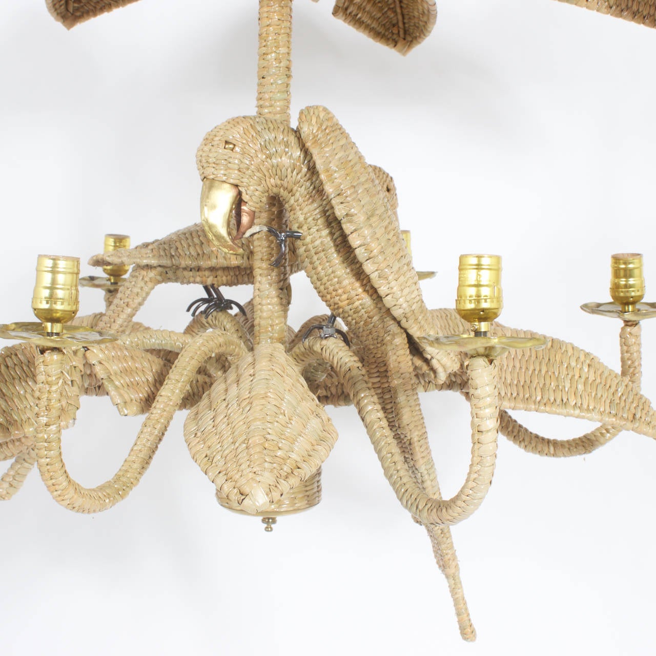 Mario Torres midcentury 6-light chandelier constructed of an iron frame wrapped with wicker or reed in an intricate tight weave. Featuring 2 busy and playful parrots with brass and copper beaks surrounded by 2 layers of palm fronds creating a fun