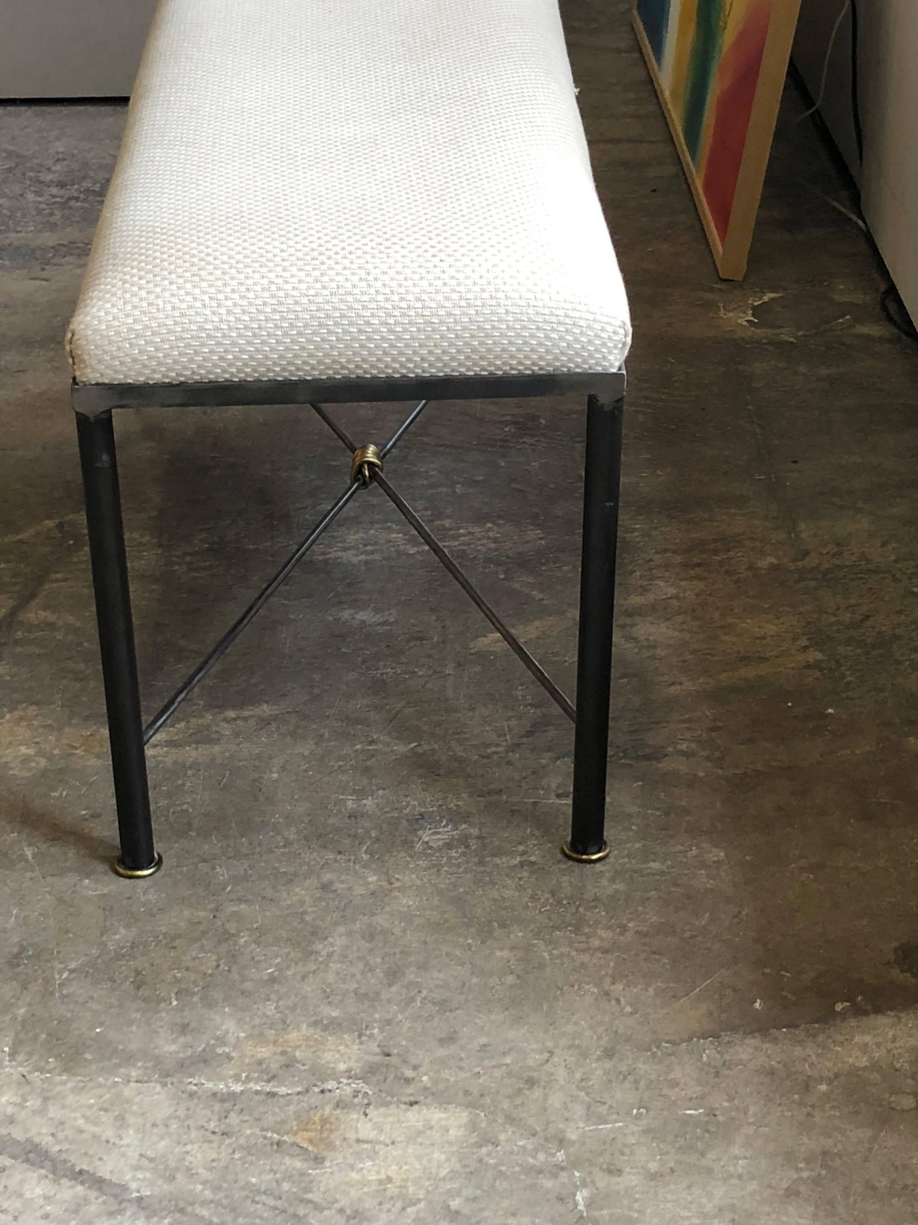 A late 20th century iron, brass and upholstered bench created by Mario Villa having a neutral cream cotton/wool upholstered seat connecting to legs that have a cross stretcher banded by Mr. Villa's distinctive twisted brass technique element; all