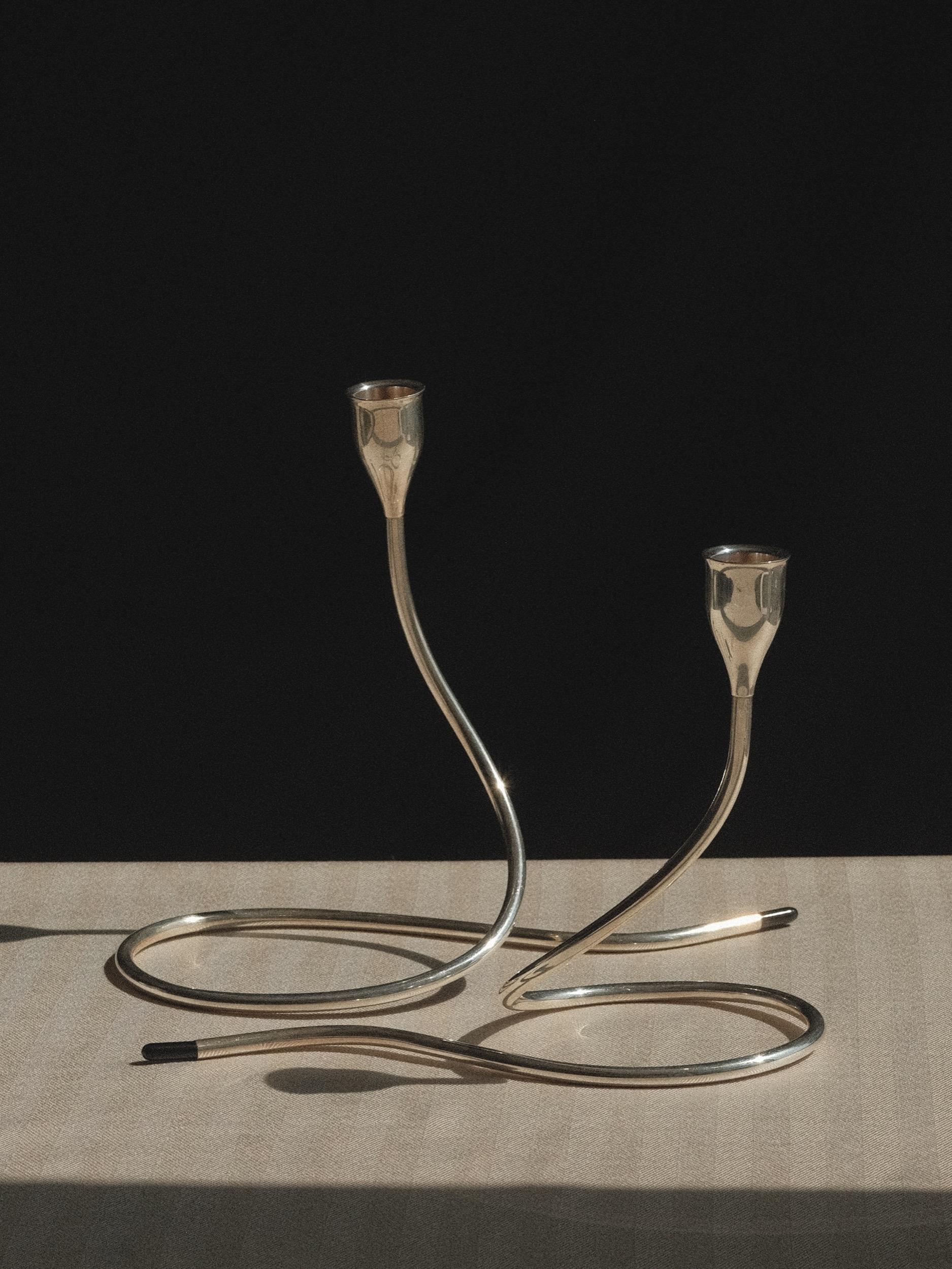 Paar Serpentine-Kerzenleuchter
Entworfen von Marion Anderson Noyes (1907-2002) für Towle Silversmiths
Der ausgestellte Kerzenbecher sitzt auf einem röhrenförmigen, geschwungenen Stiel, der sich romantisch ineinander verschlingen oder skulptural für