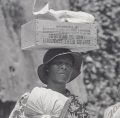 "2 Mujeres Negras Llevando Paquetes - Una Lleva Sobre la Cabeza Excedentes de Productos de Socorro"
