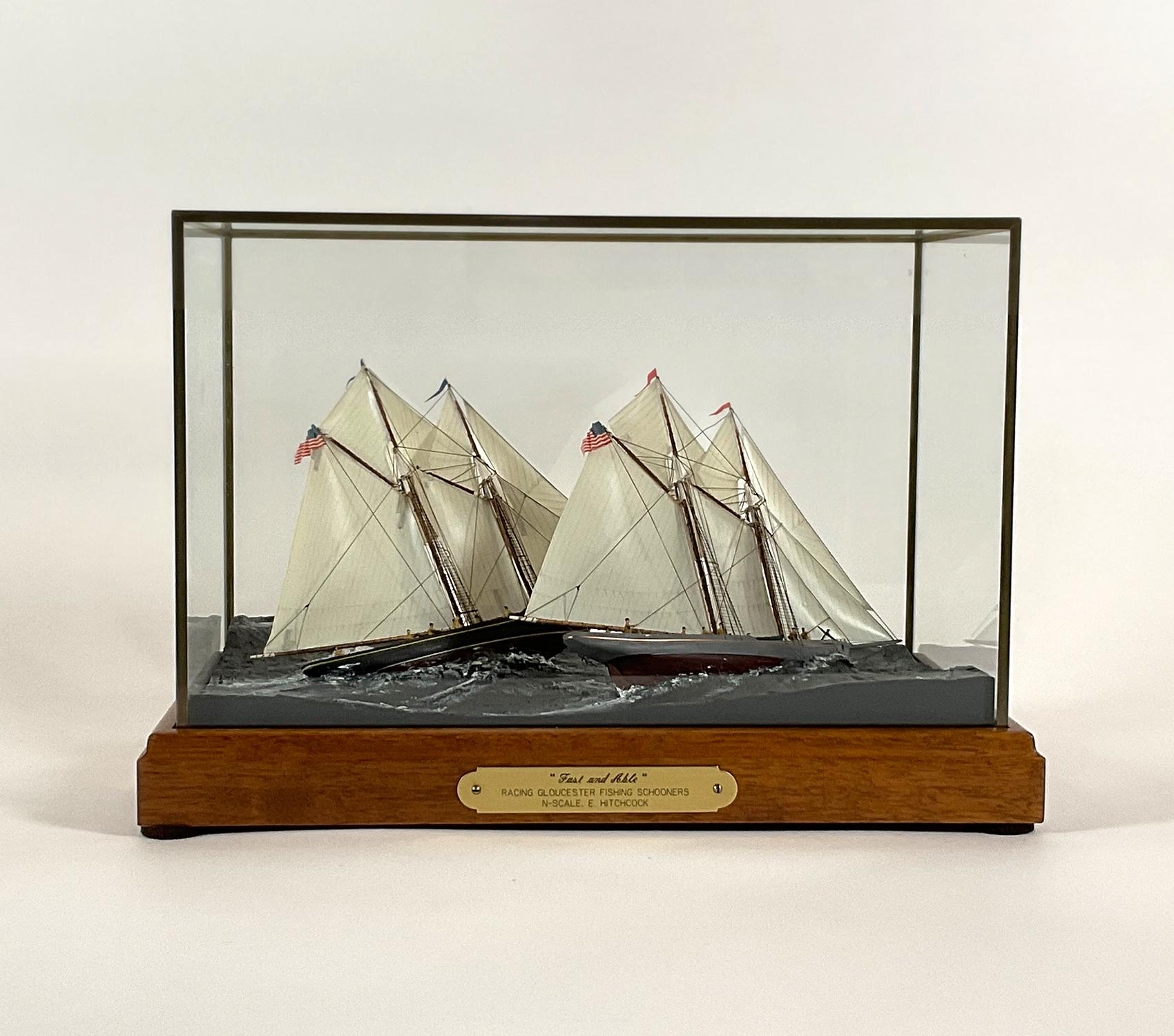 Fabulous nautical diorama showing two Gloucester fishing schooners racing under full sail with crews on board. Vessel details include cabins, hatches, dories, companion ways, helms, etc. Set into a composition ocean sailing at an angle through