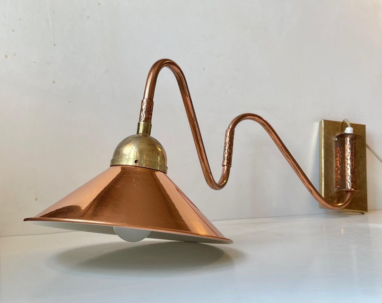 Fully adjustable wall lamp composed of solid brass, copper and featuring a copper shade with white reflective inner shade. It has a styling very much in line with nautical - maritime environments. It was manufactured during the 1960s probably by E.